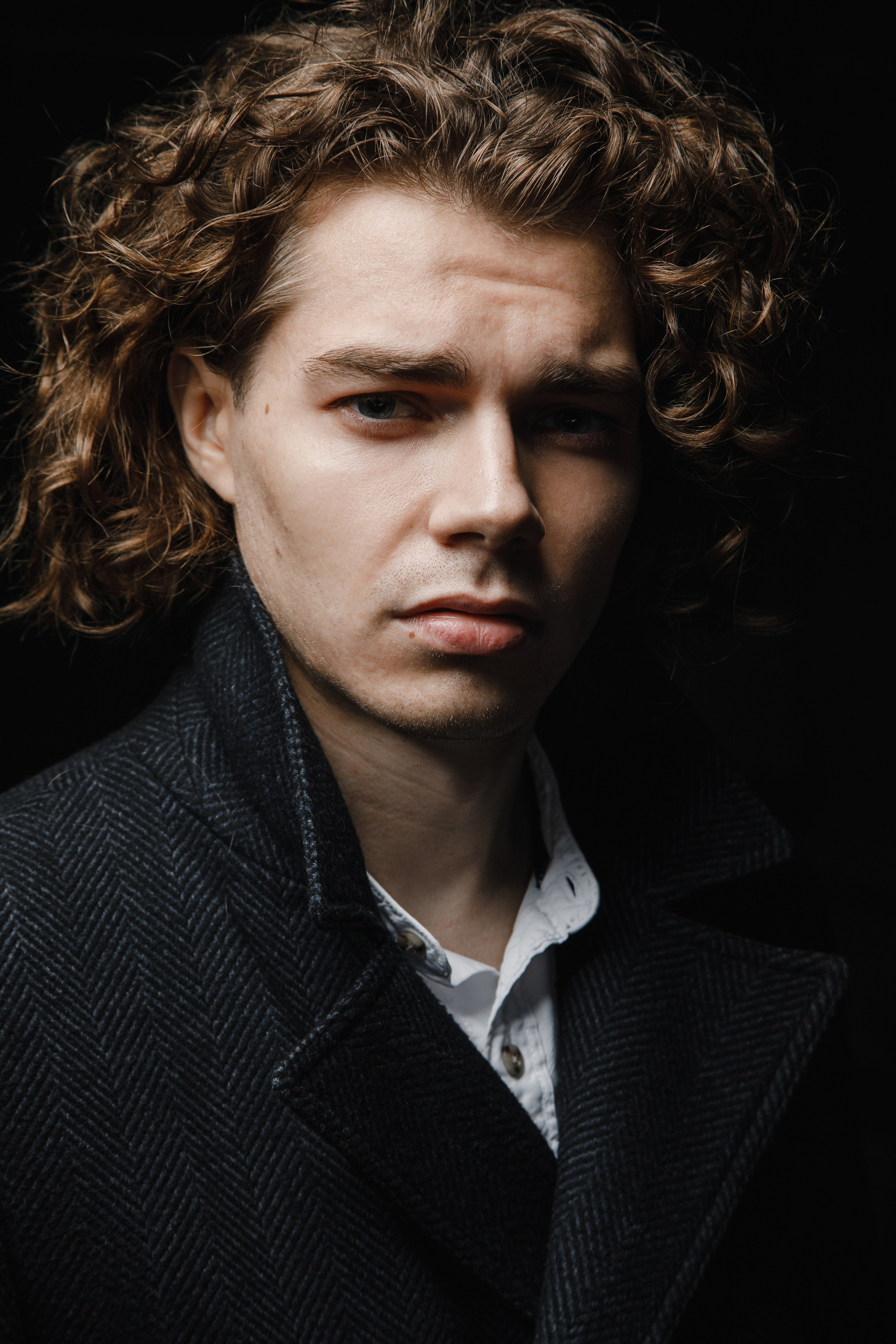 Портрет мужчины на черном студийном фоне.