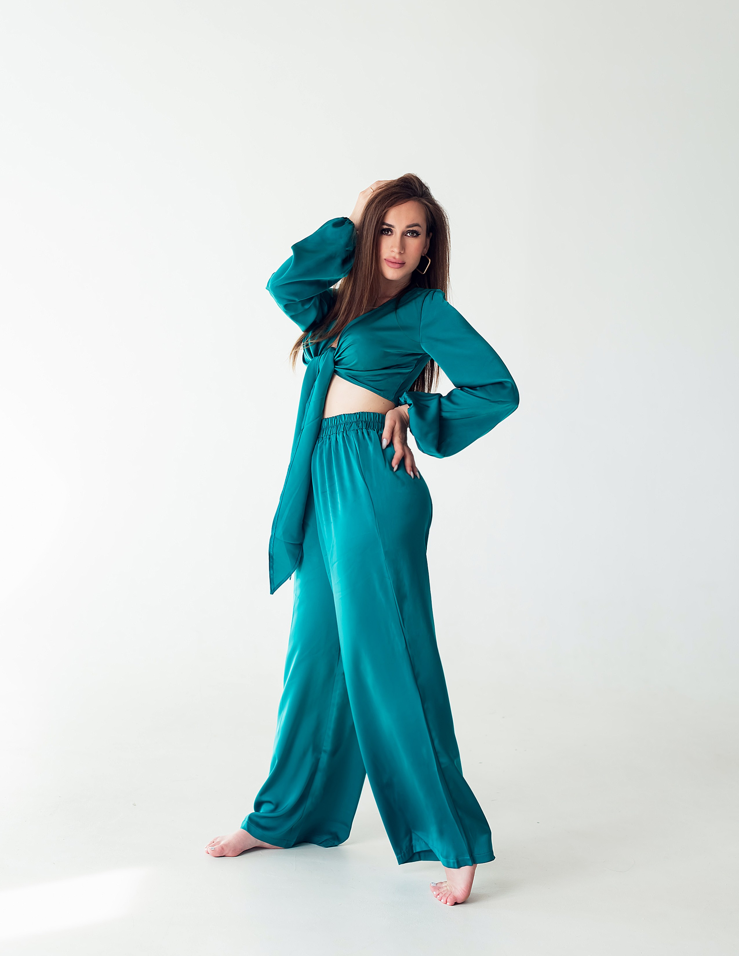 Красивая девушка в изумрудном костюме пижамного стиля, фотоссесия на циклораме в студии.