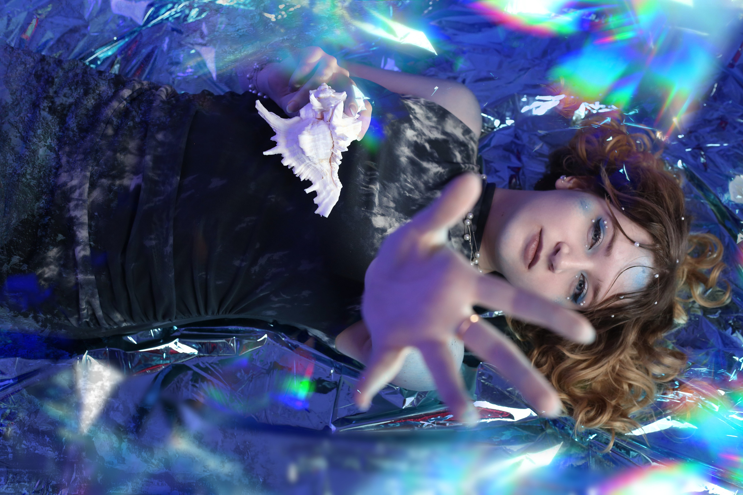 Мистическая фотосессия: девушка в черном платье лежит в воде с раскрытой ладонью