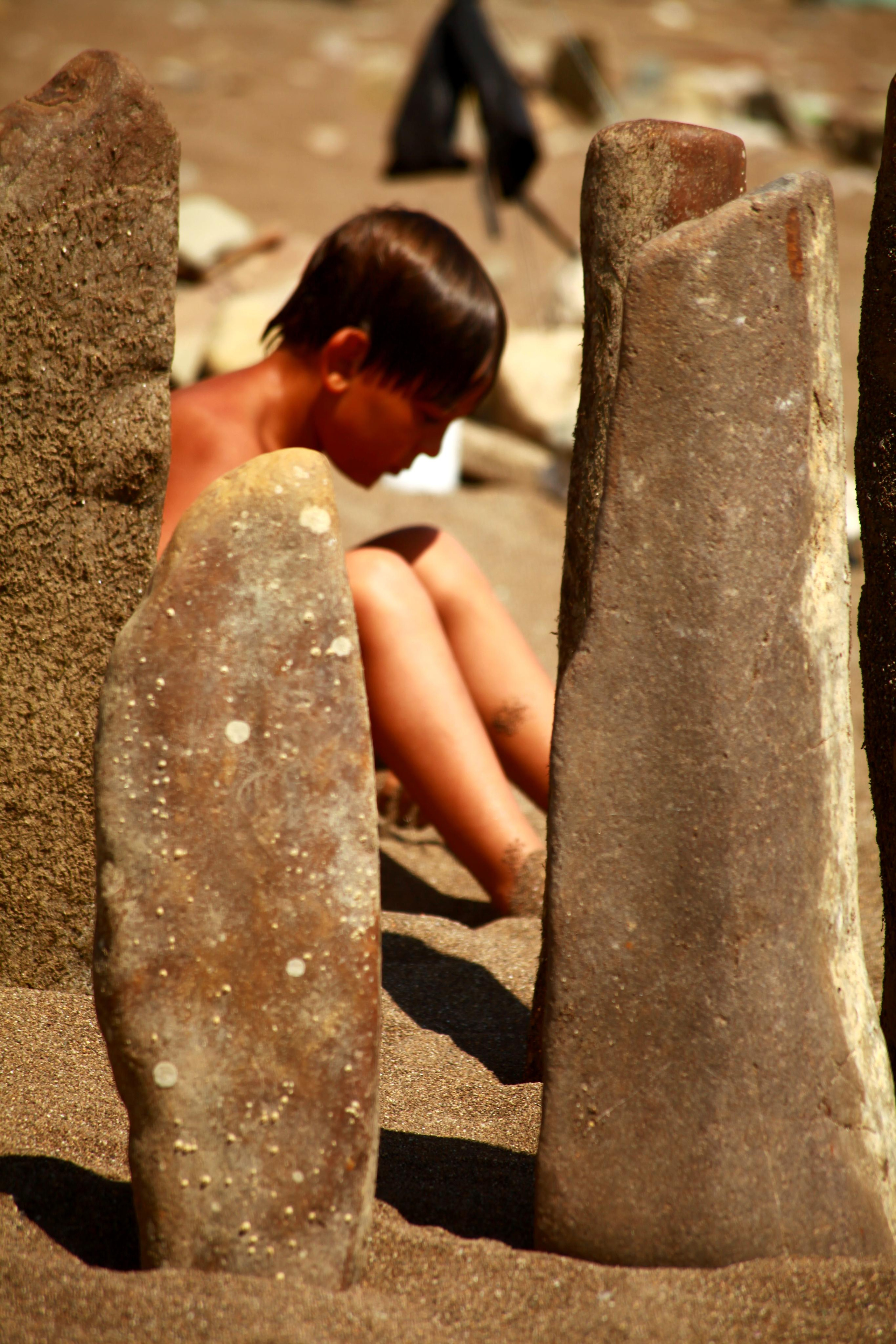 Крым, голый мальчик сидит между большими камнями