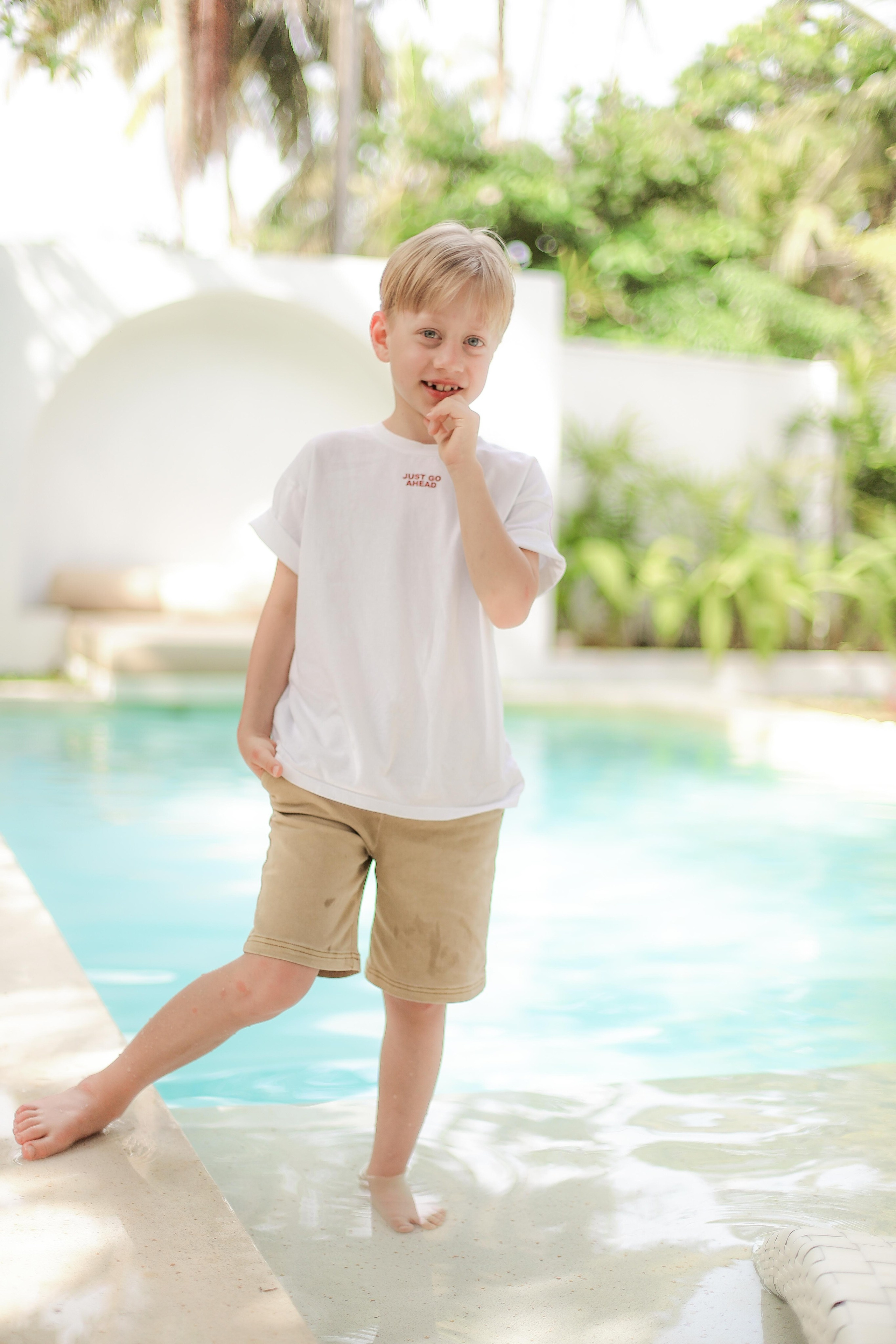 «Сын смеётся у воды: золотые блики на поверхности бассейна»