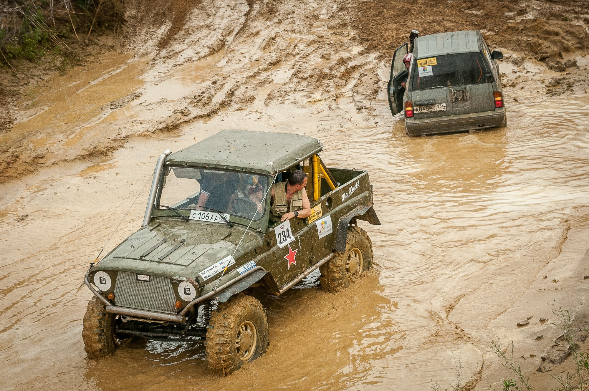 Водитель УАЗика смотрит за застрявшем в грязи автомобилем