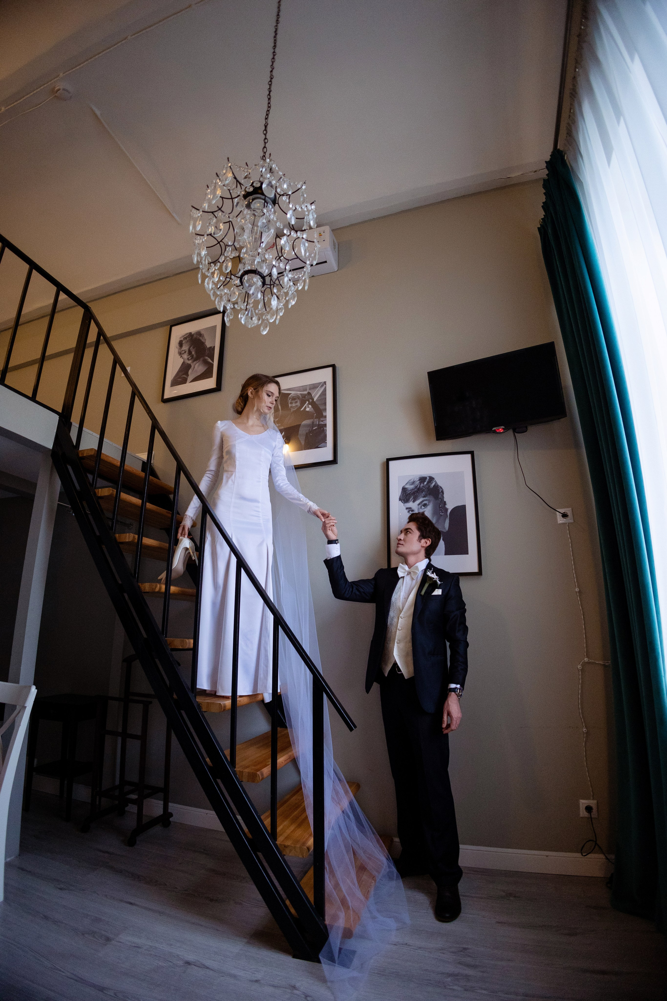 Жених протянул руку невесте спускающейся по лестнице.