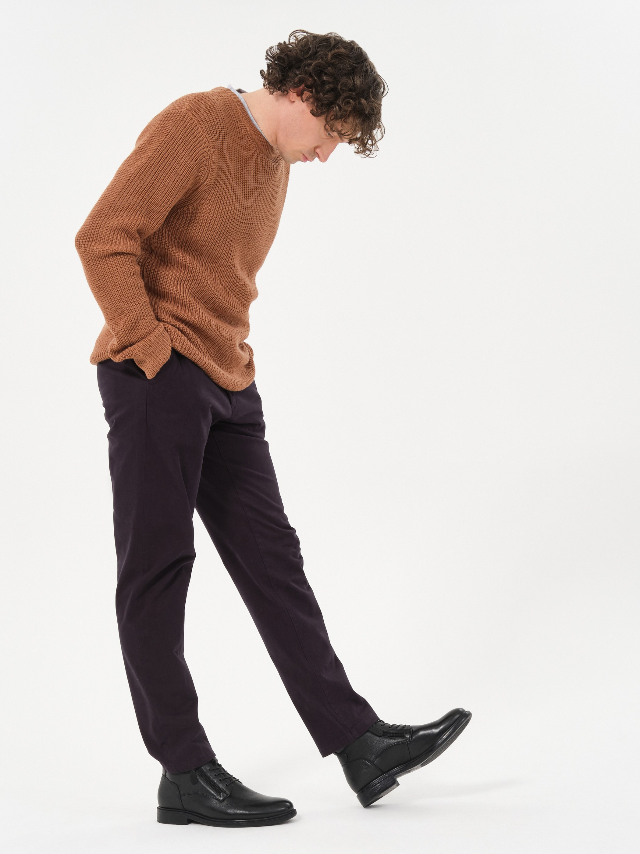 Мужчина в коричневом свитере и темных брюках