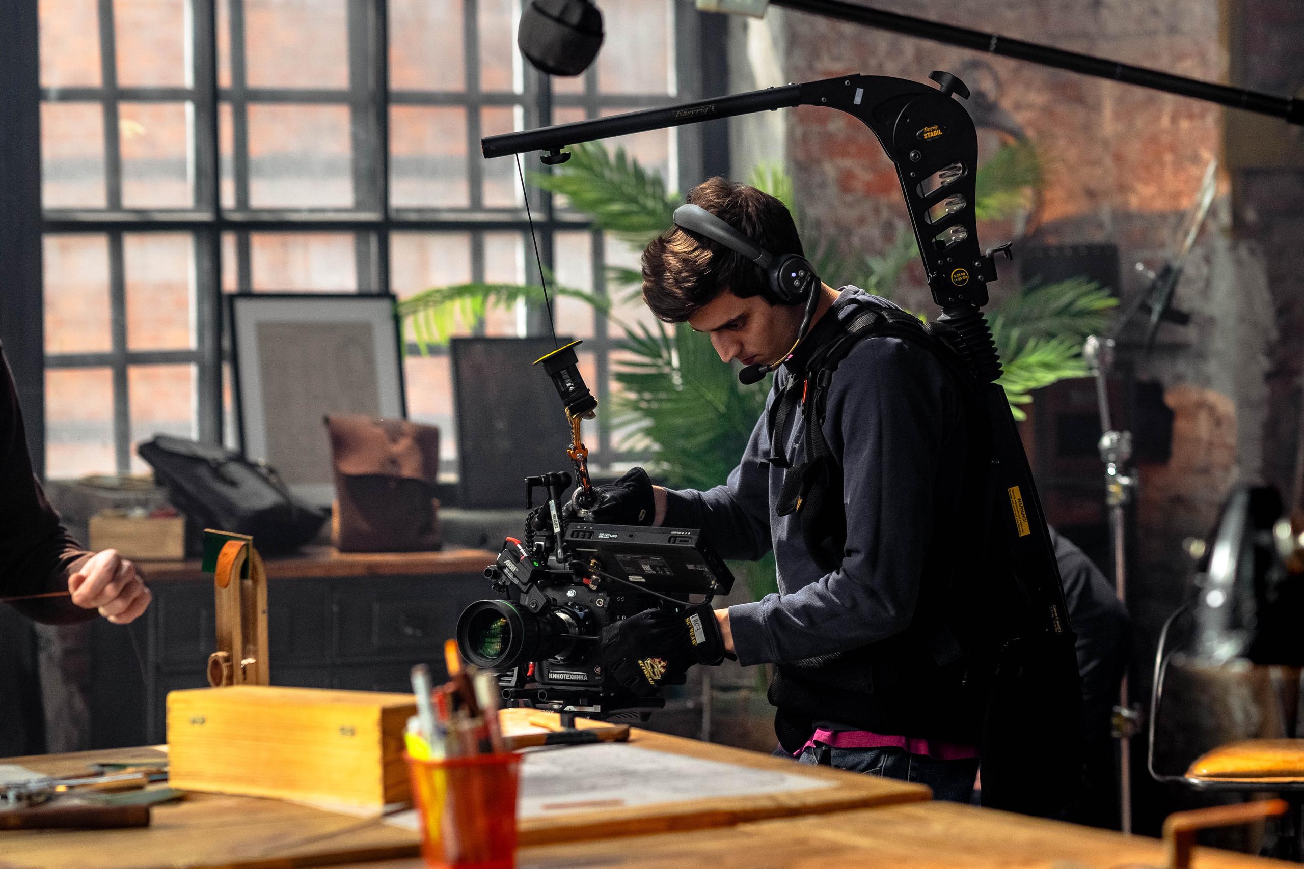 Оператор с видеокамерой в руках снимает крупные планы кожевенного инструмента, лежащего на столе