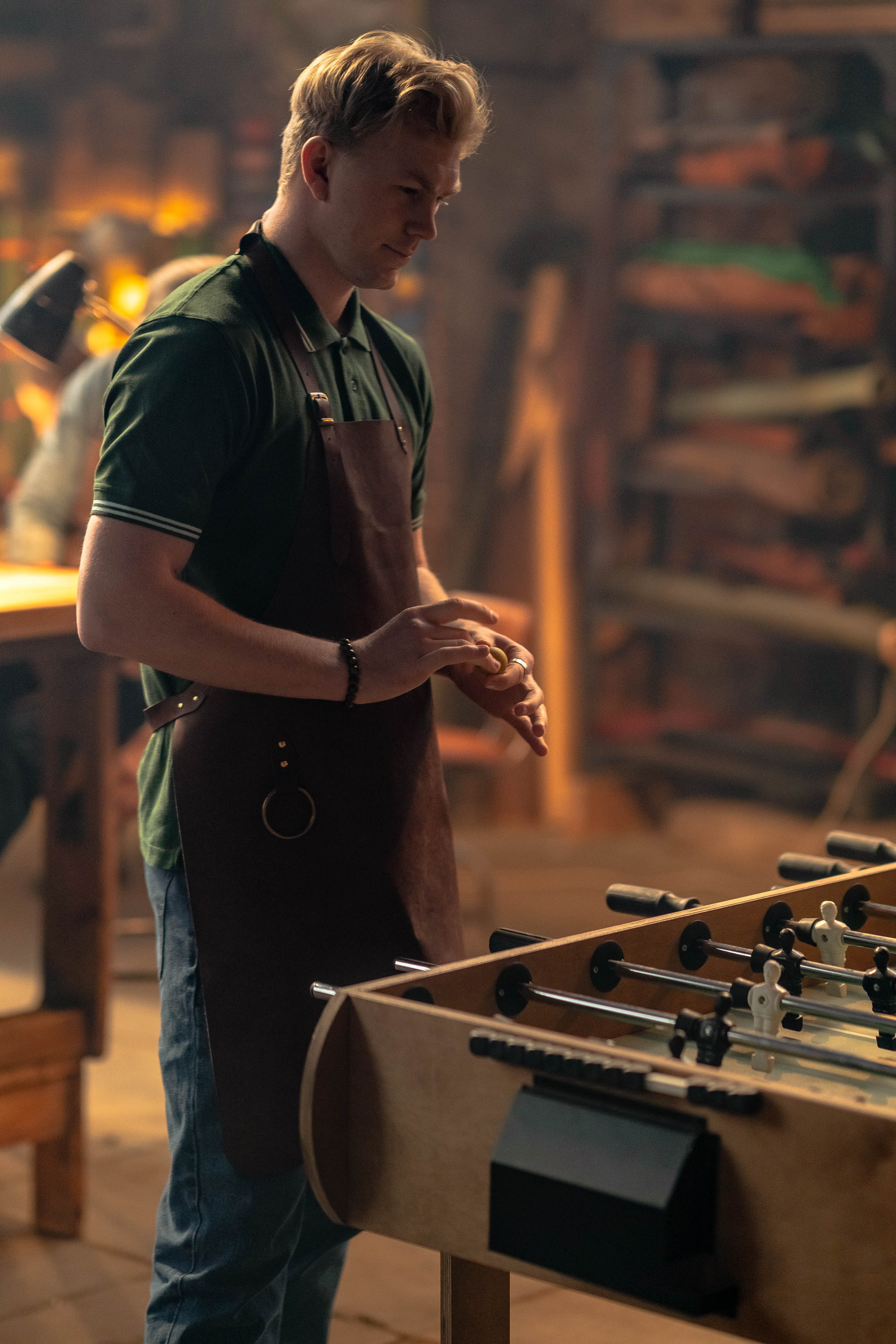 Молодой парень в кожаном фартуке играет в мини-футбол