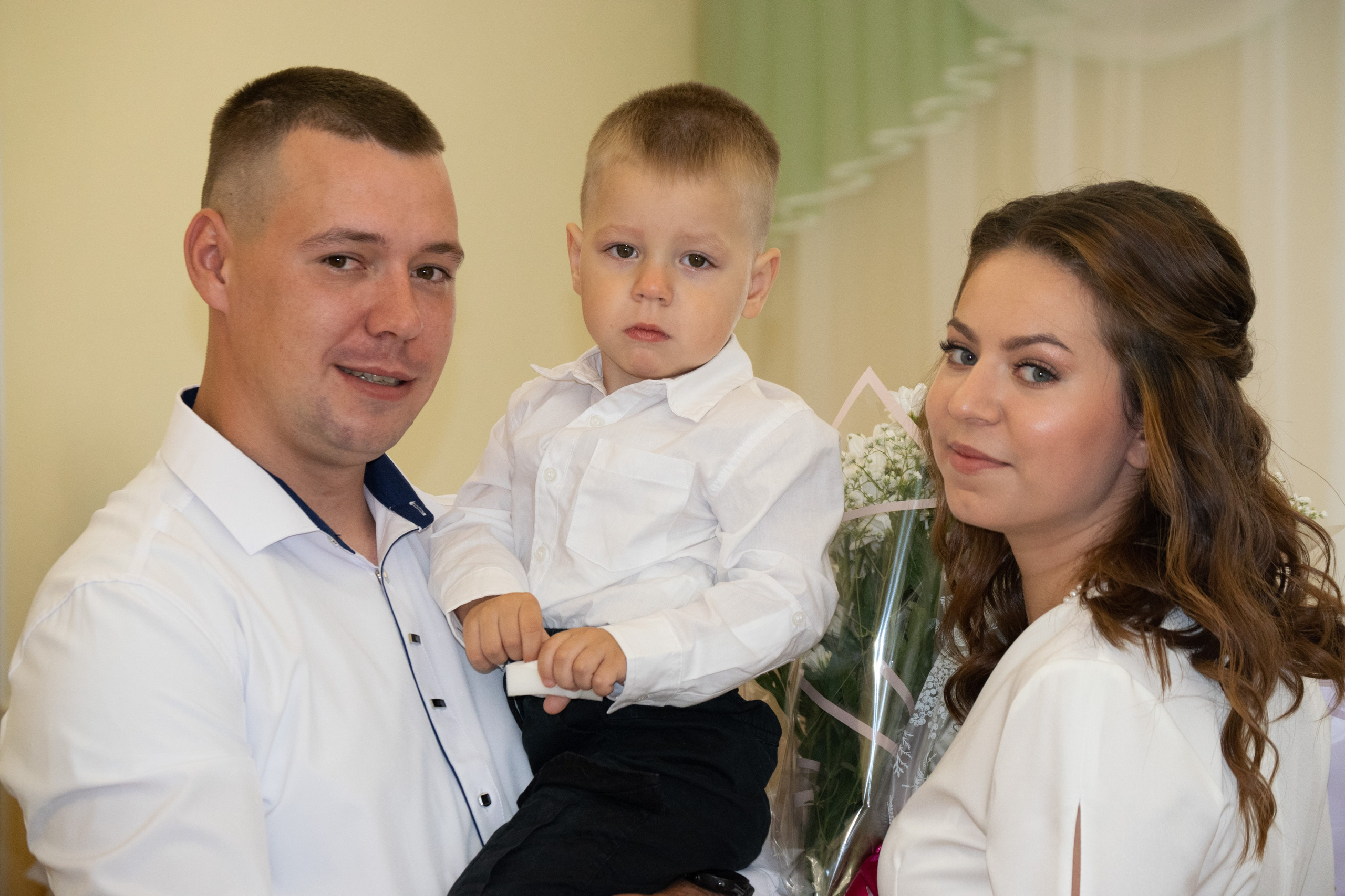 Свадебная фотосессия в  в Сортавальском Загсе Карелия. Невеста, жених и маленький мальчик на руках у мужчины.