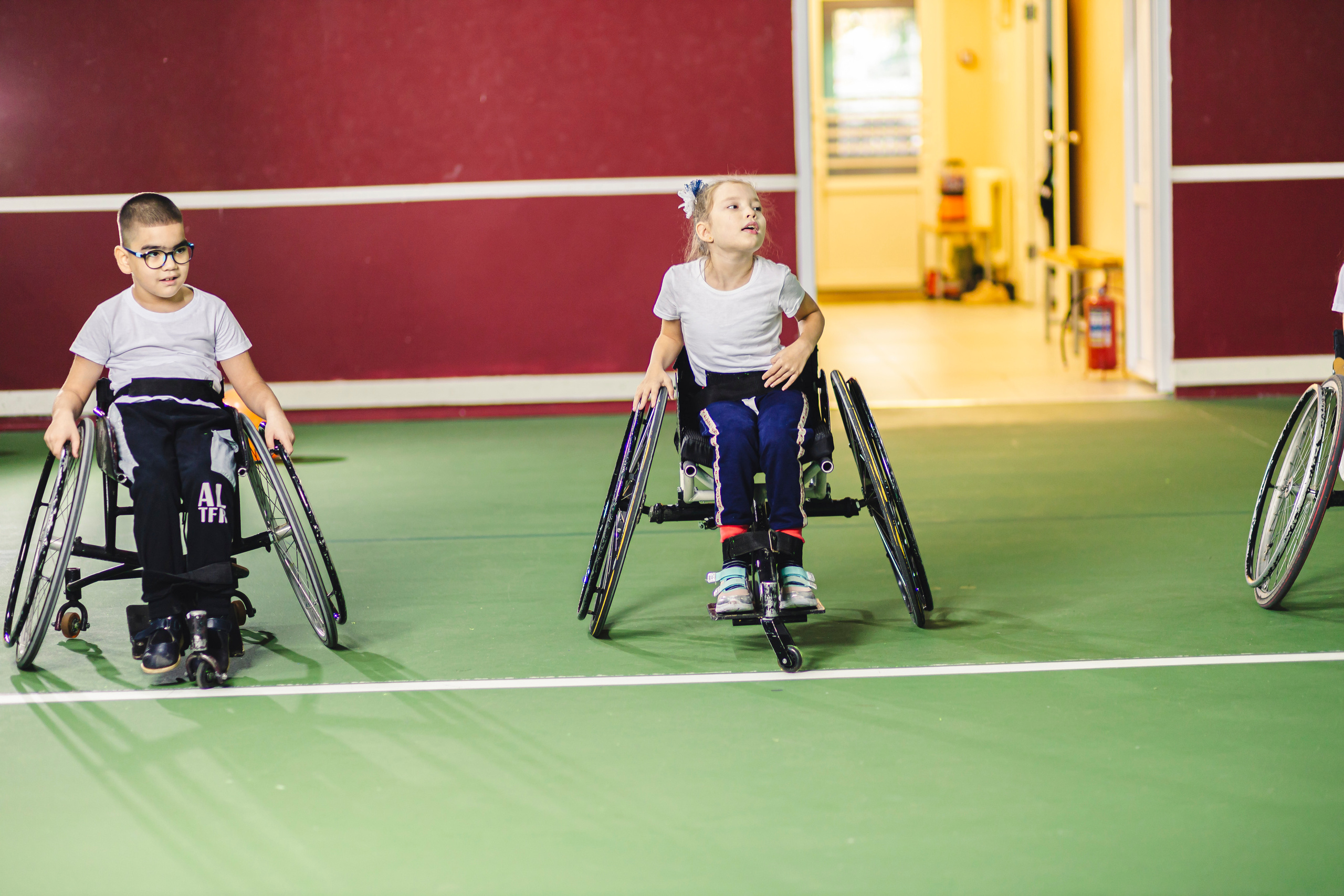 дети на колясках в спорт зале готовятся к тренировкам 