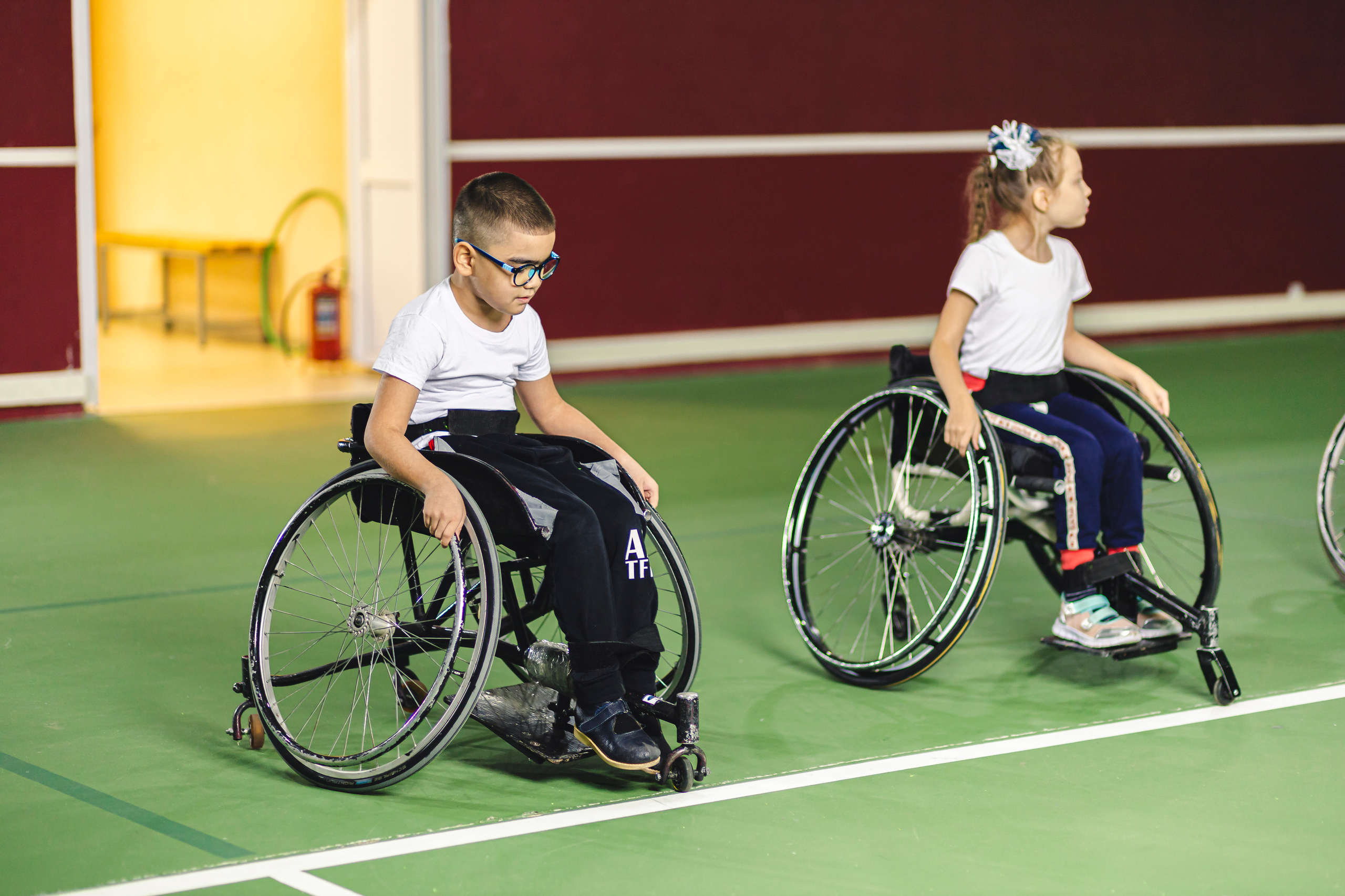 двое детей на колясках в спорт зале 