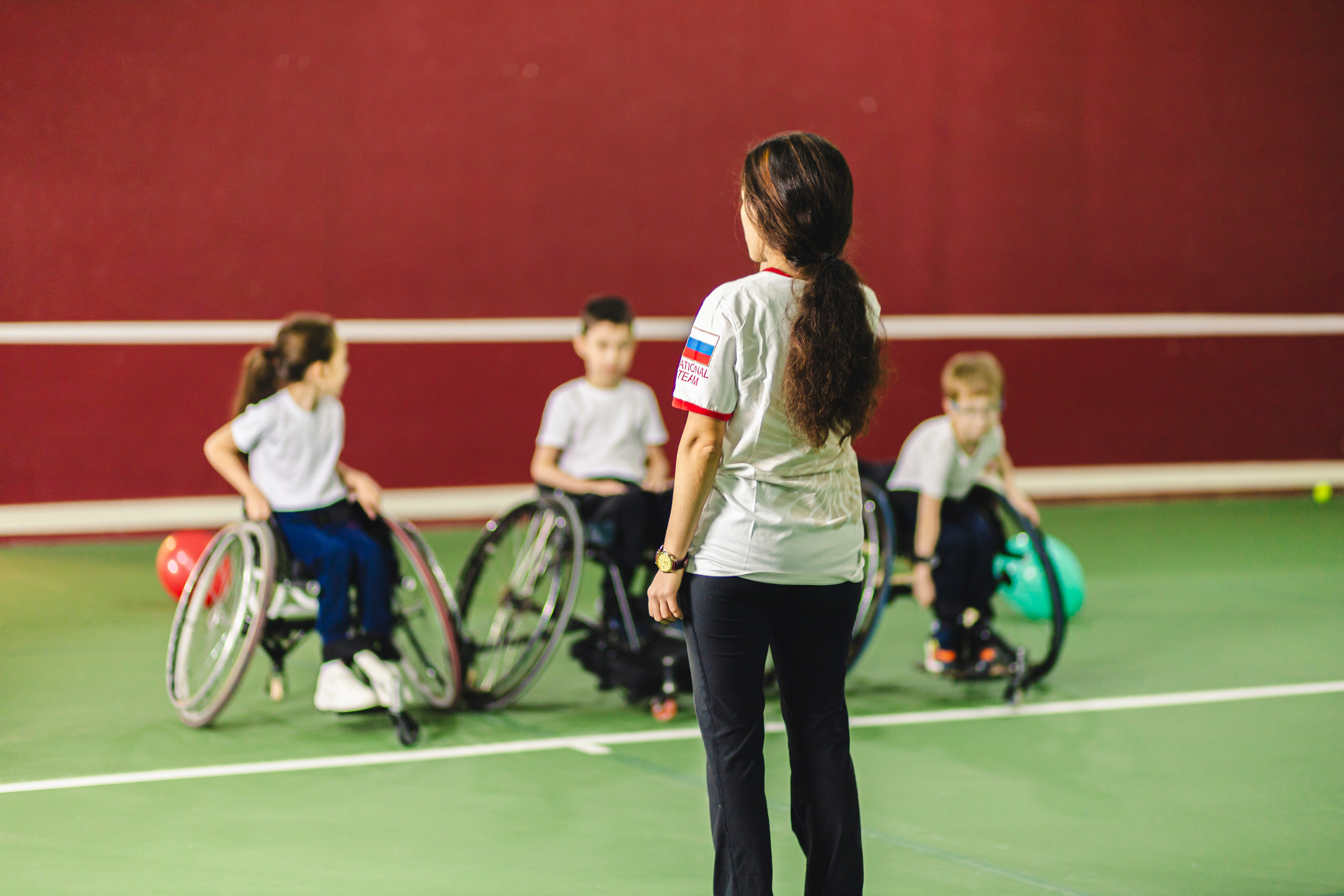 Девушка спортсмен объясняет детям правила игры в теннис 