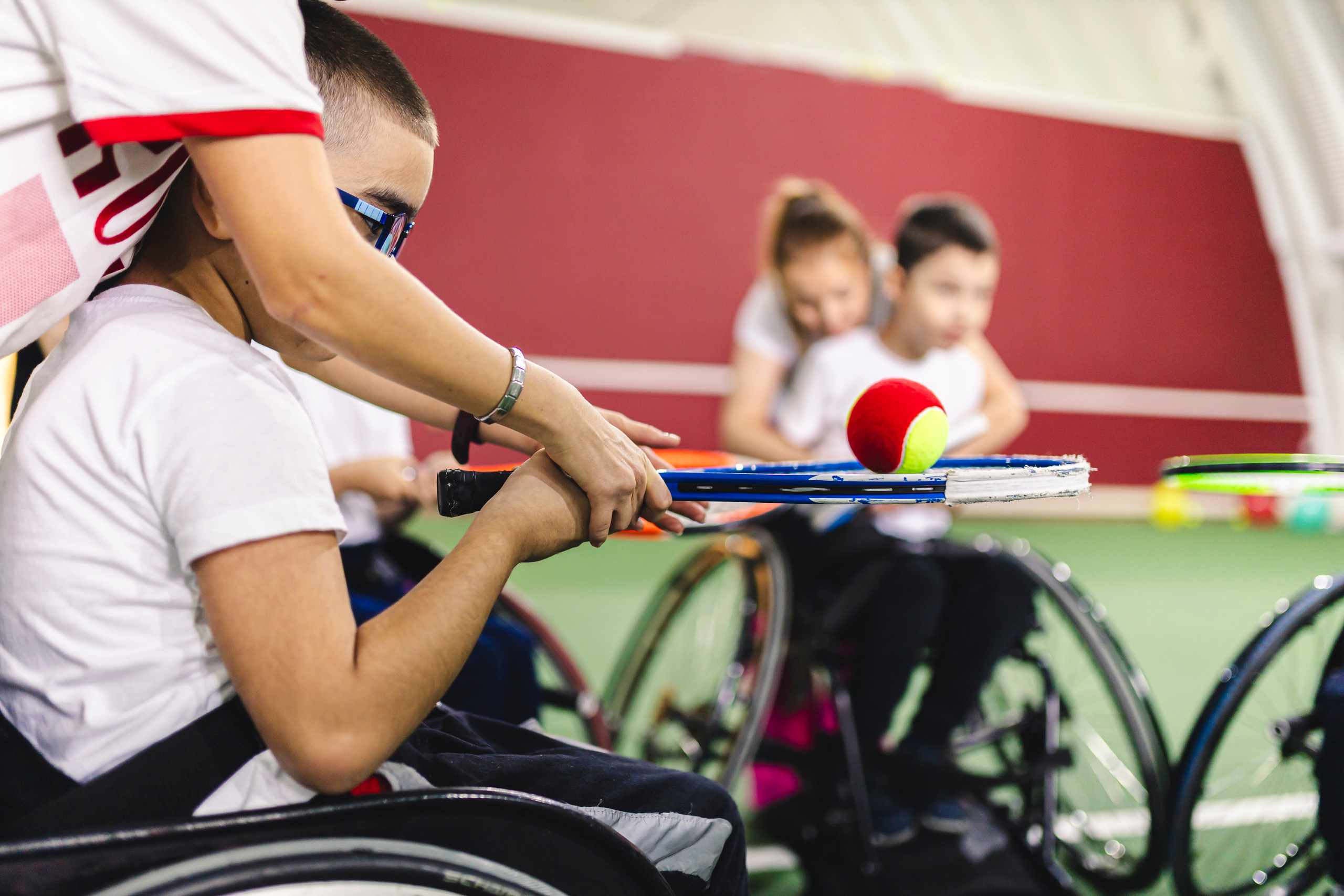 ребенок на коляске с теннисной ракеткой и мячом 