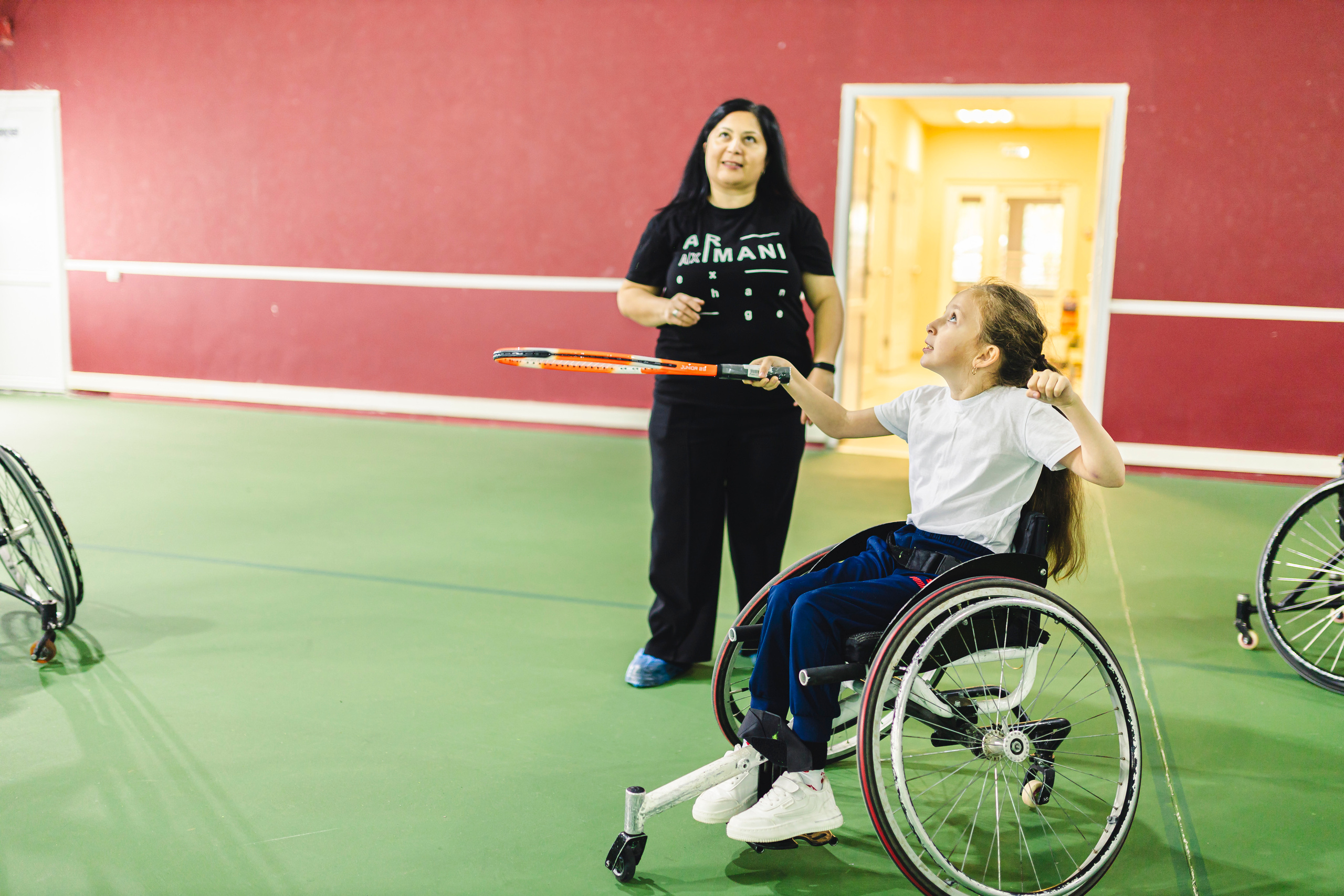 Девочка играет в теннис ракеткой сидя на коляске 
