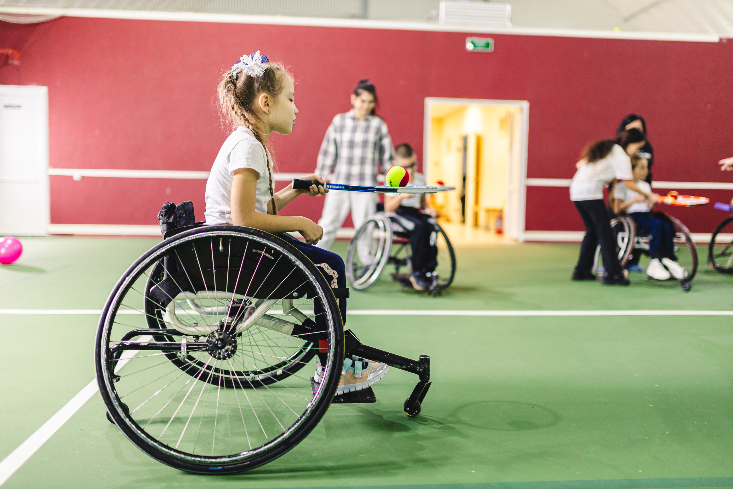 Ребенок на коляске играет в теннис 