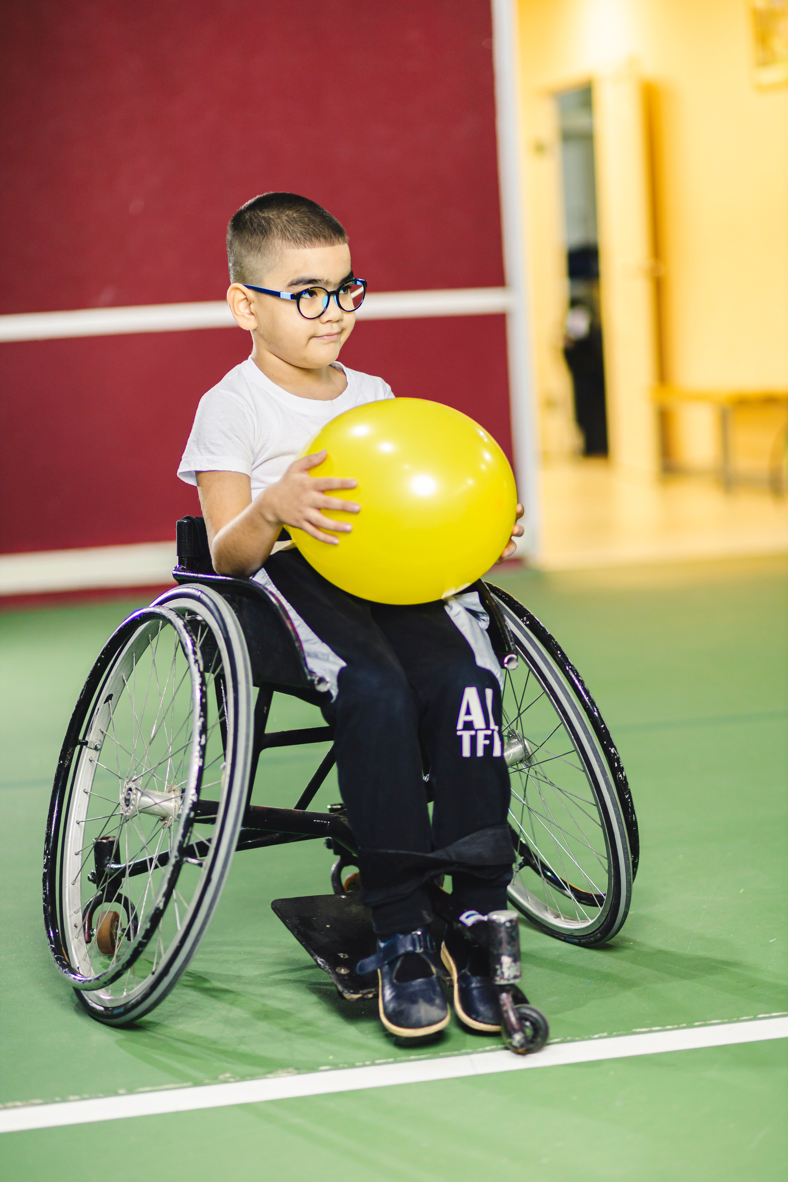 мальчик на коляске в белой футболке и с желтым воздушным шариком 