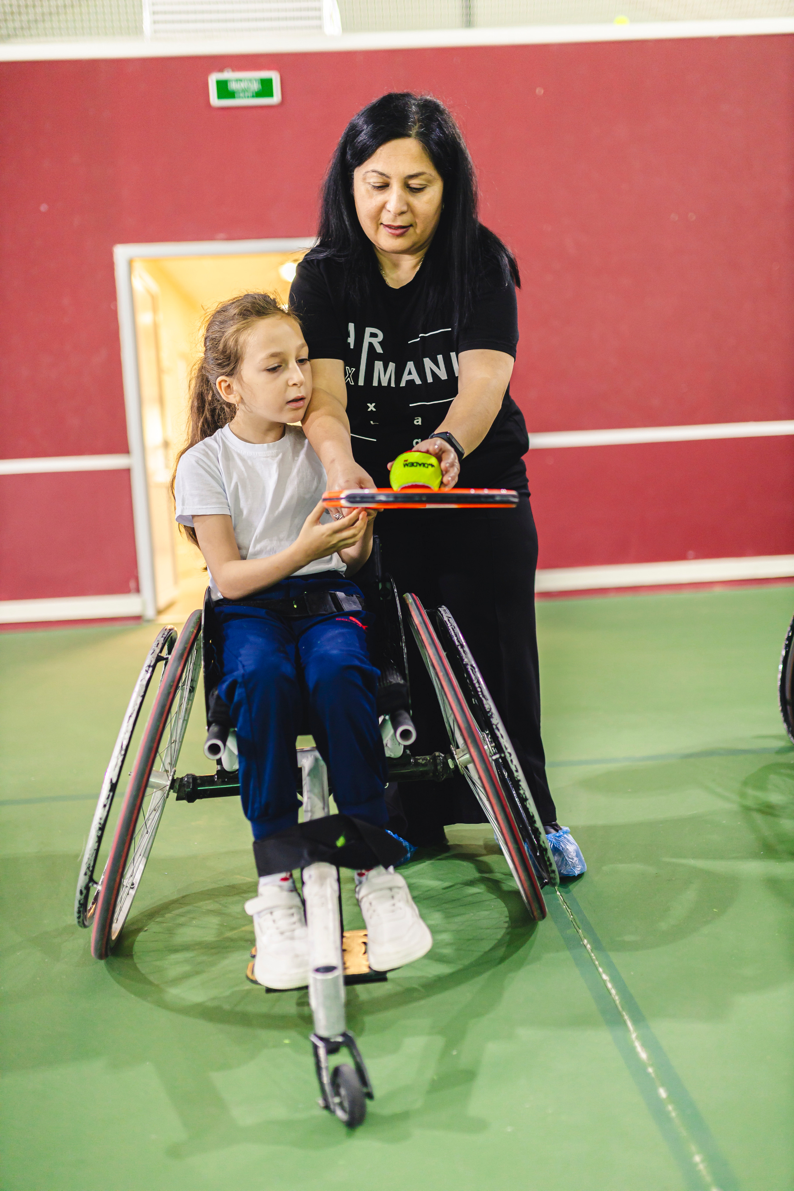 мама с дочкой играют в теннис на колясках 