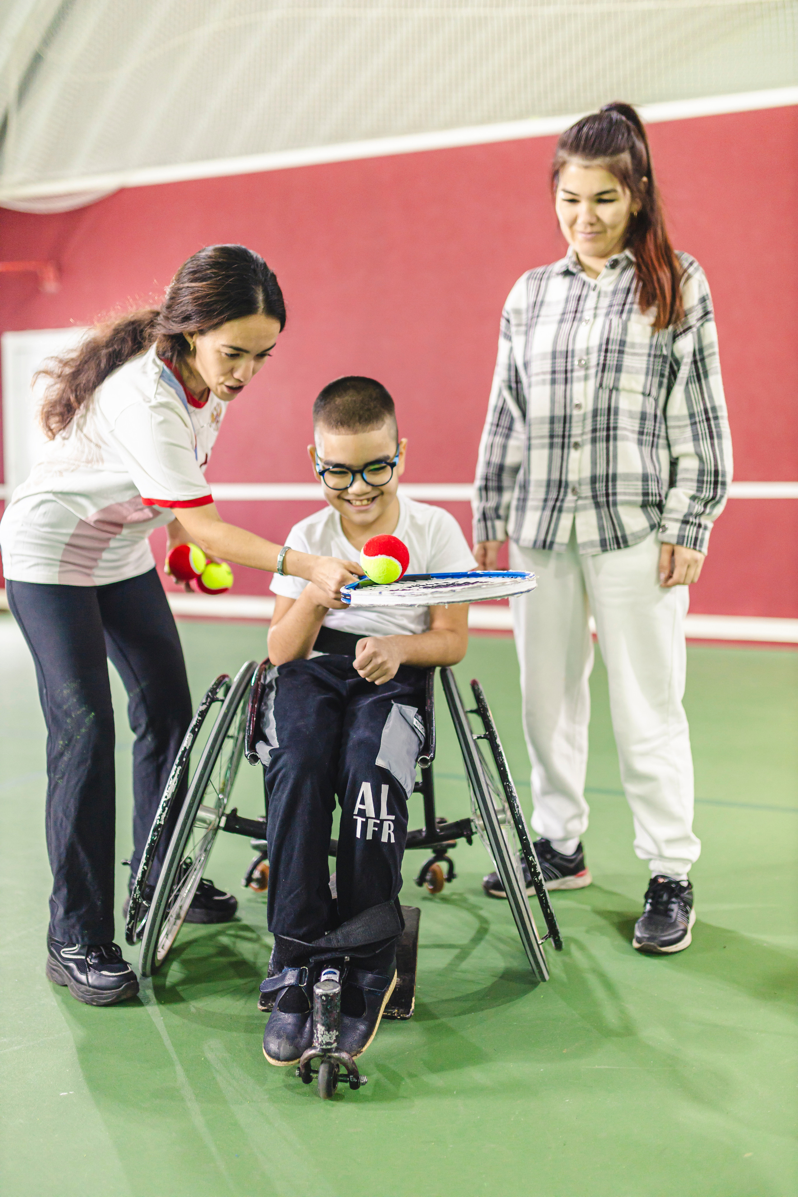 Девушка обучает мальчика играть в теннис 