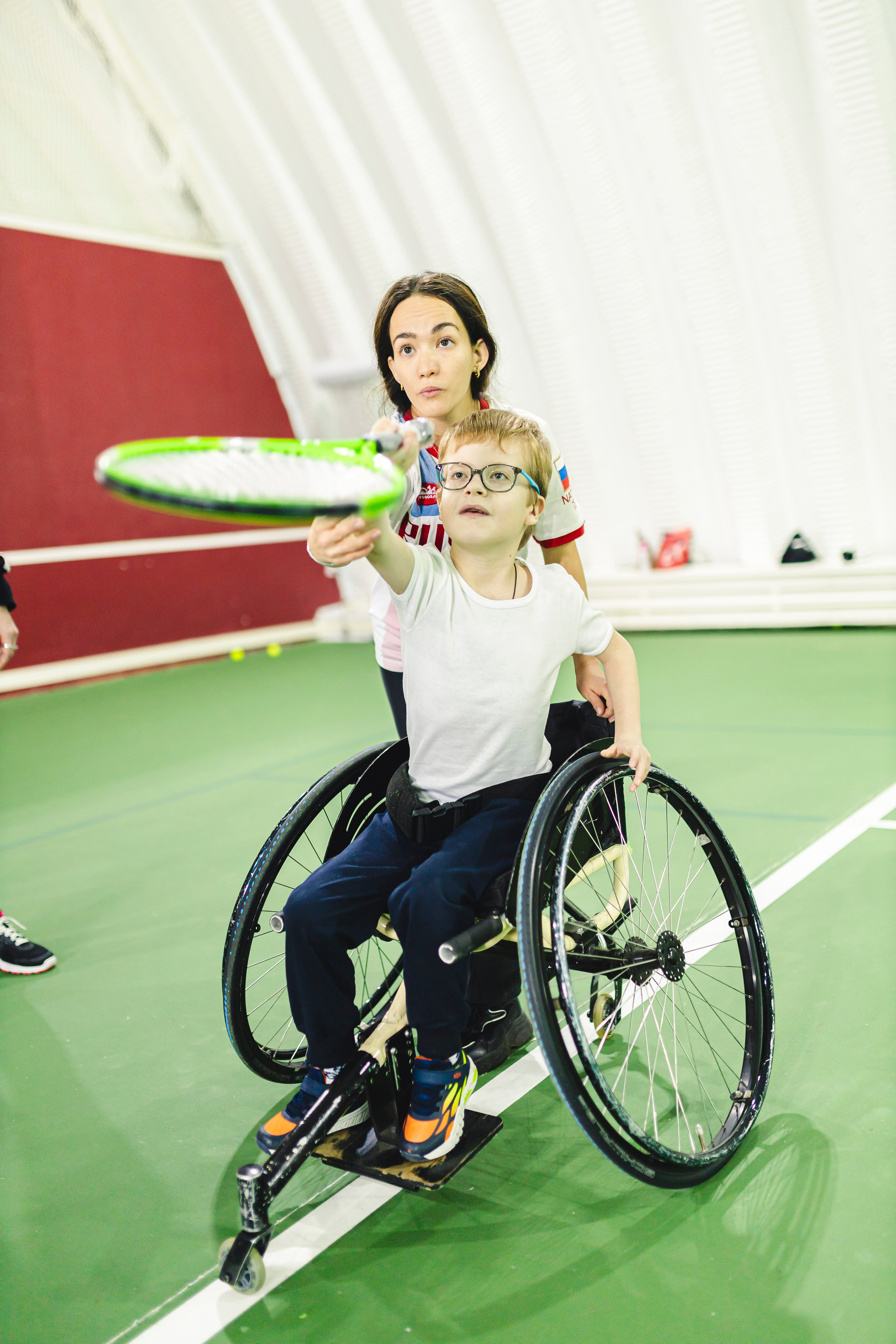 девушка играет в теннис с мальчиком на коляске 