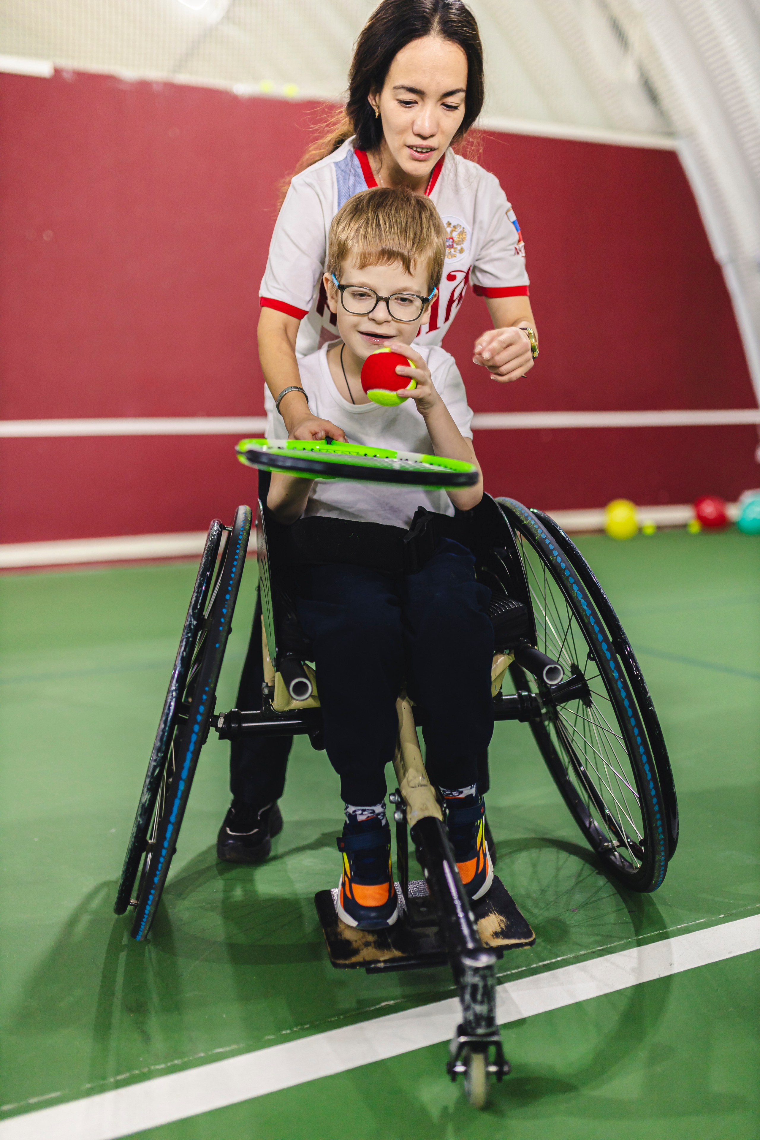 тренер помогает научиться играть в теннис 