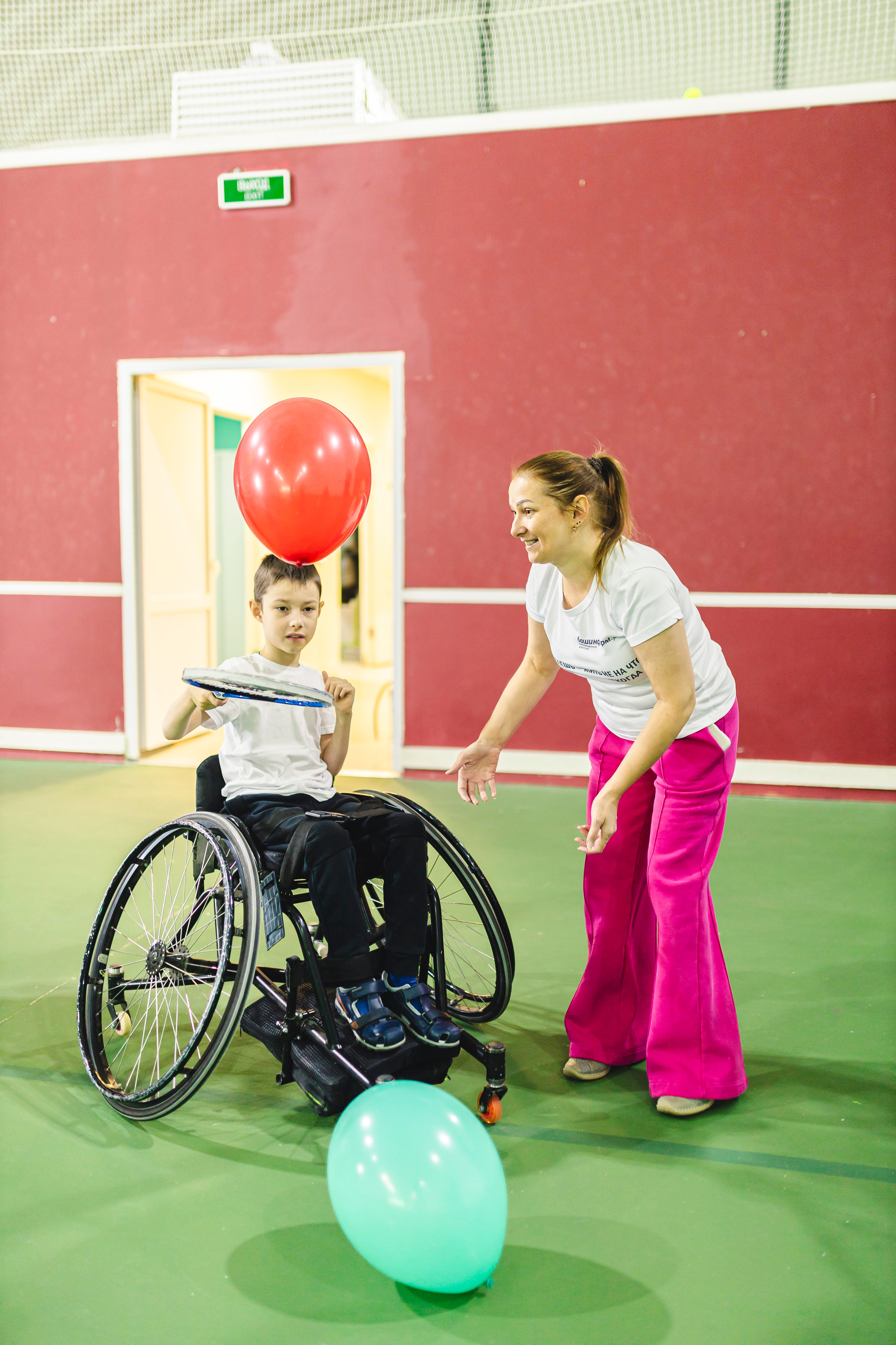 Мама с сыном играет теннисной ракетой с воздушными шариками 