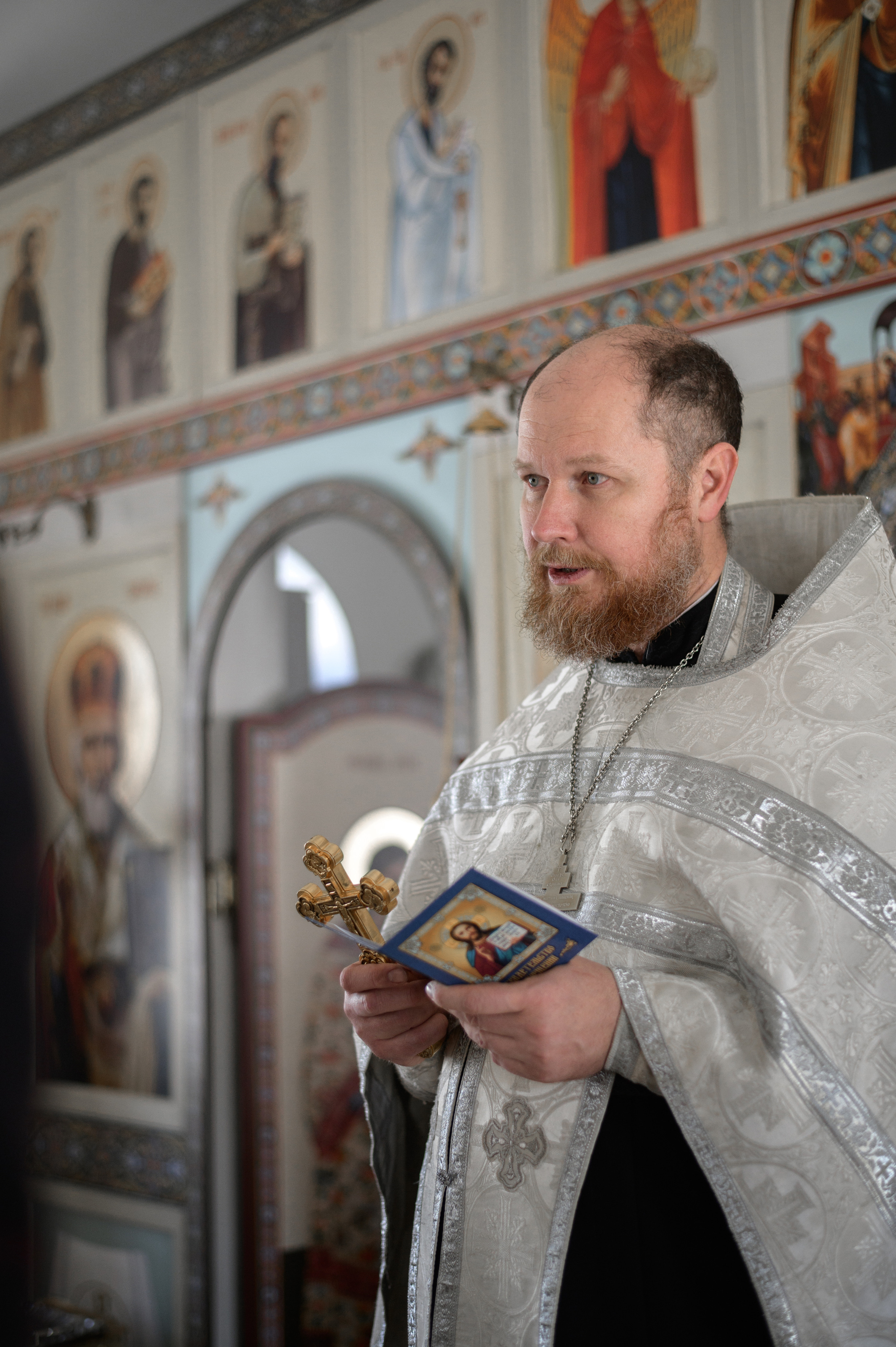 батюшка в церкве у иконостаса читает молитву