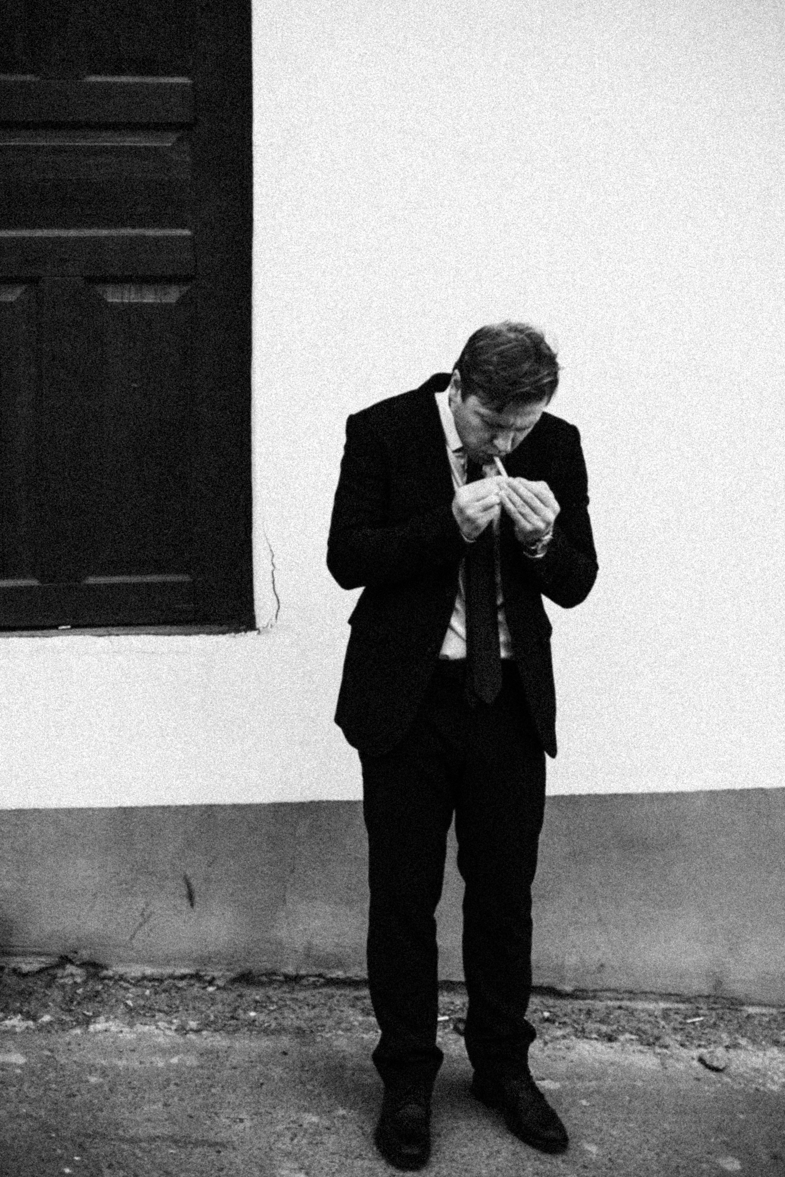 Мужчина в костюме прикуривает у входа
