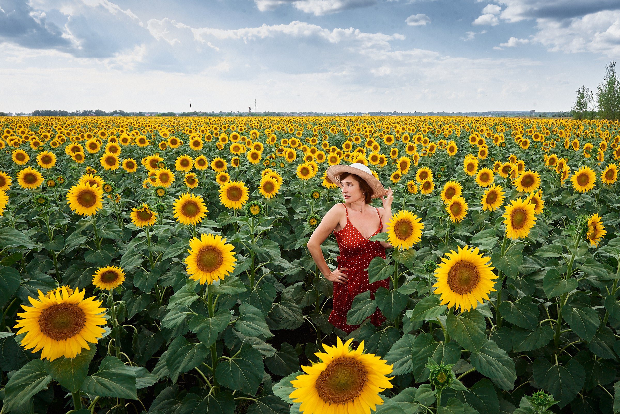 брюнетка в красном платье и соломенной шляпе на огромном поле