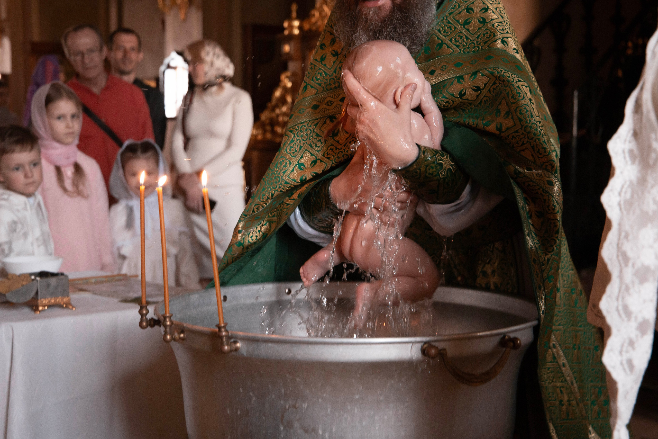 Малышка и купель во время окунания на крещение.