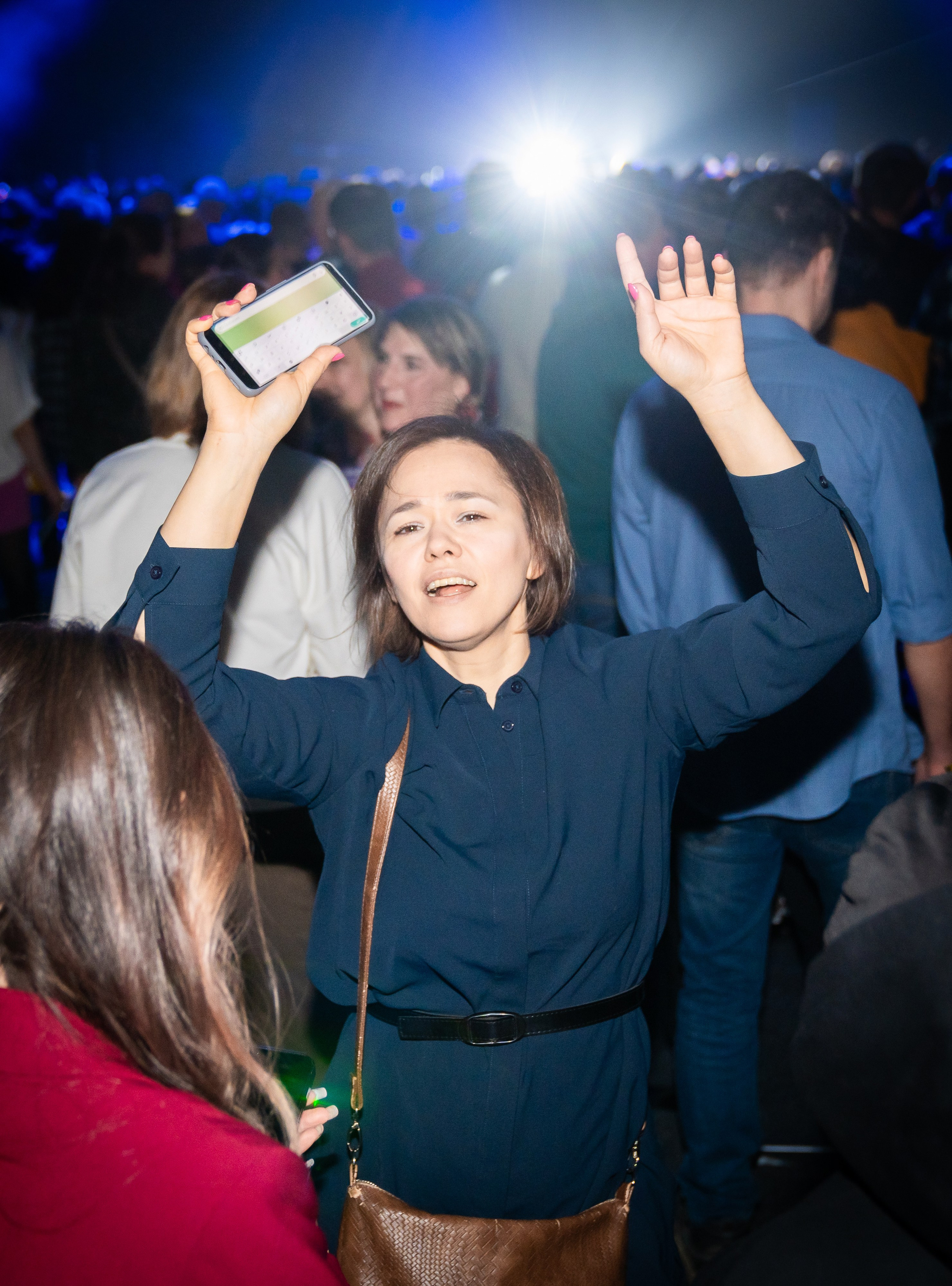 Эмоциональная девушка с телефоном и поднятой рукой на концерте Светланы Разиной. Корпоратив Ленремонт в КСК Арена. Фото Евгения Мальцева.