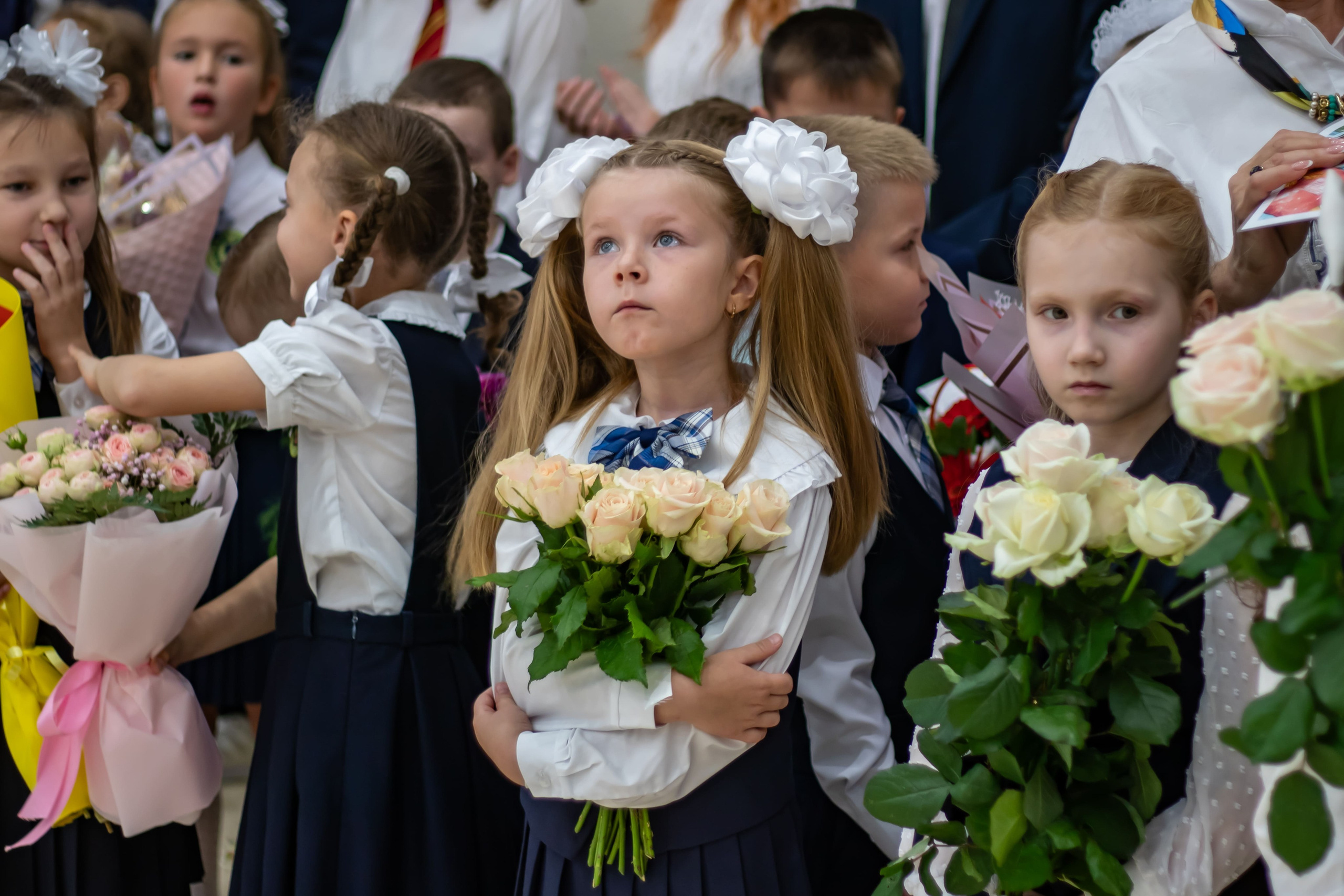 Фотограф на 1 сентября снимает учеников с праздничными букетами