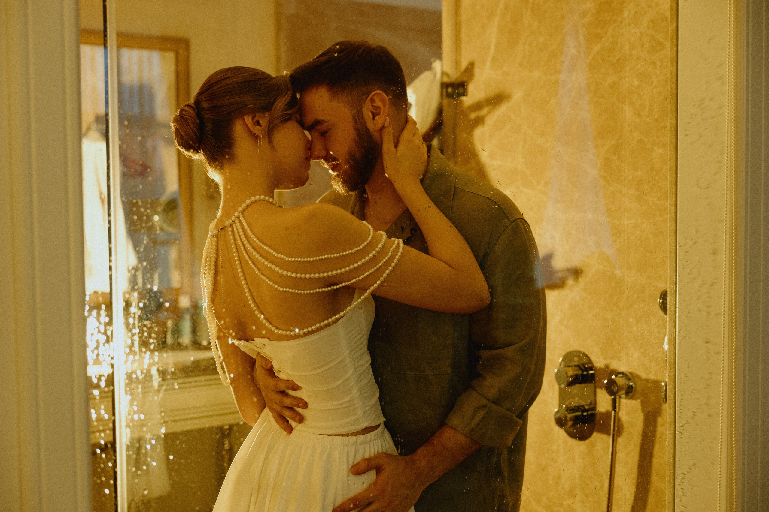 Жених и невеста страстно обнимаются в освещенной ванной.