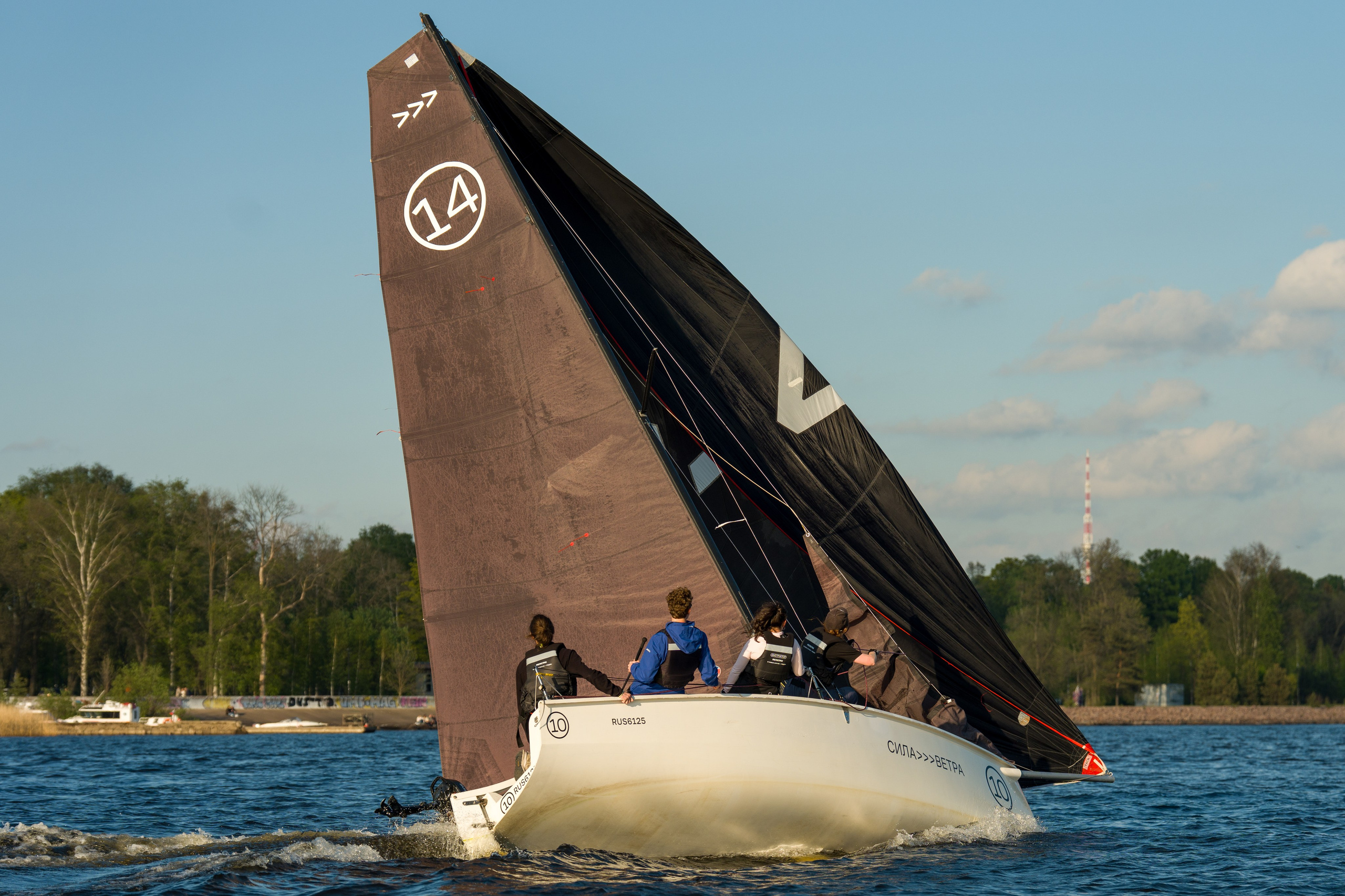 SV20 crew trims a black sail, powering upwind on chilly water