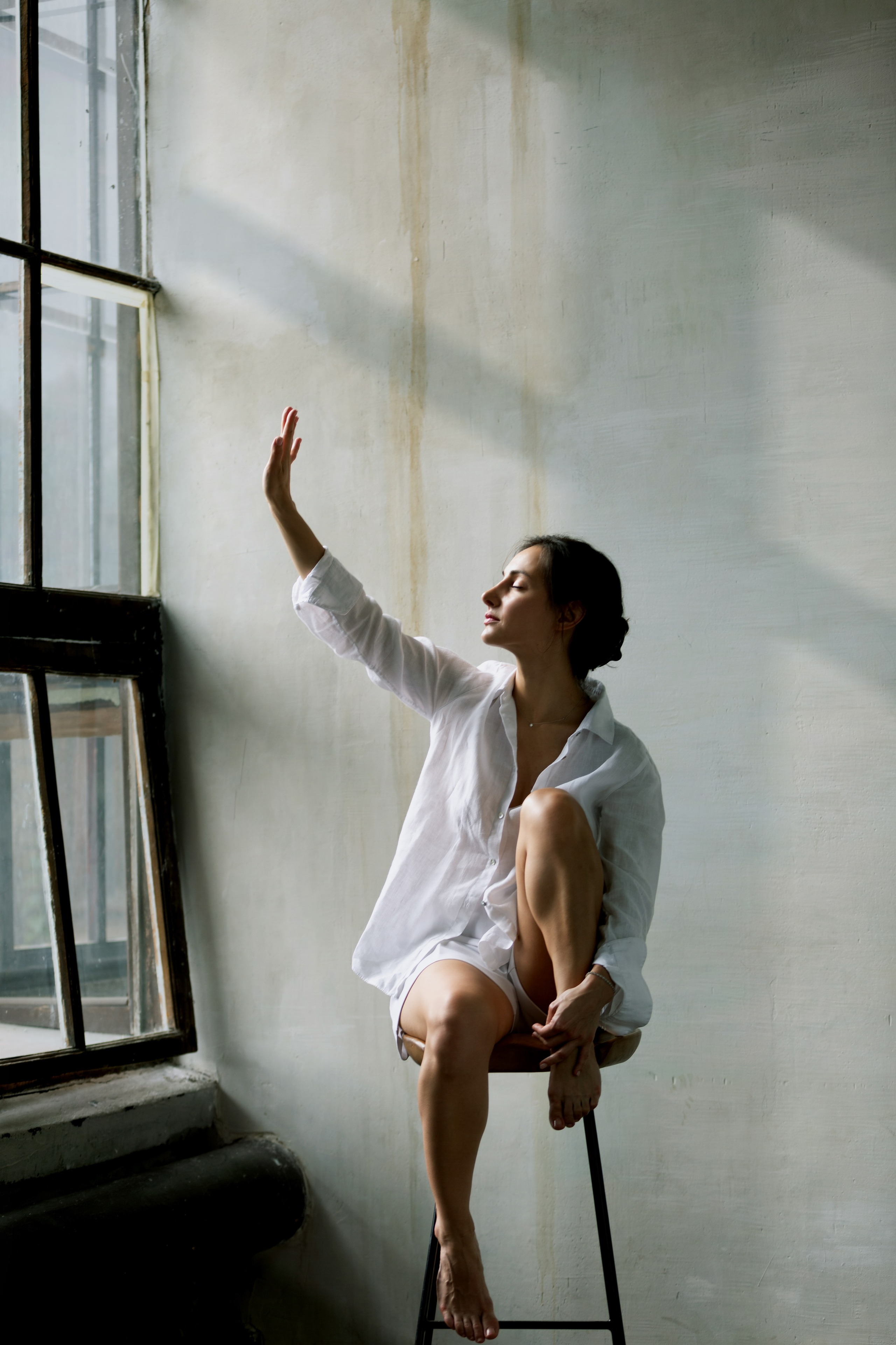 Девушка в рубашке сидит у окна — утончённая фотосессия в интерьере.