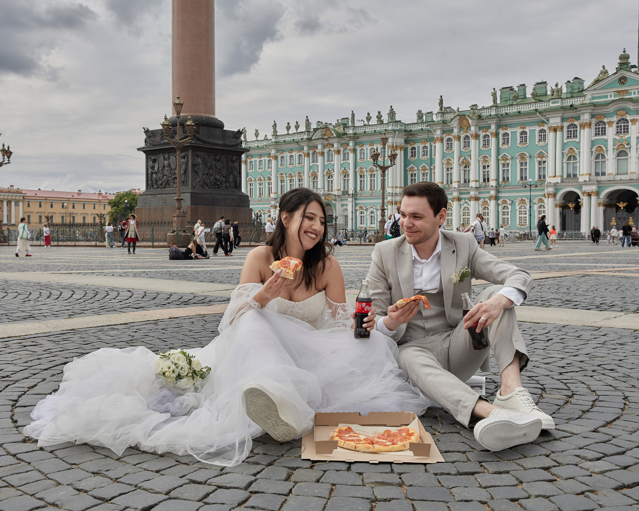 Портрет жениха и невесты на Дворцовой площади, в Санкт-Петербурге, едят пиццу и смеются.
