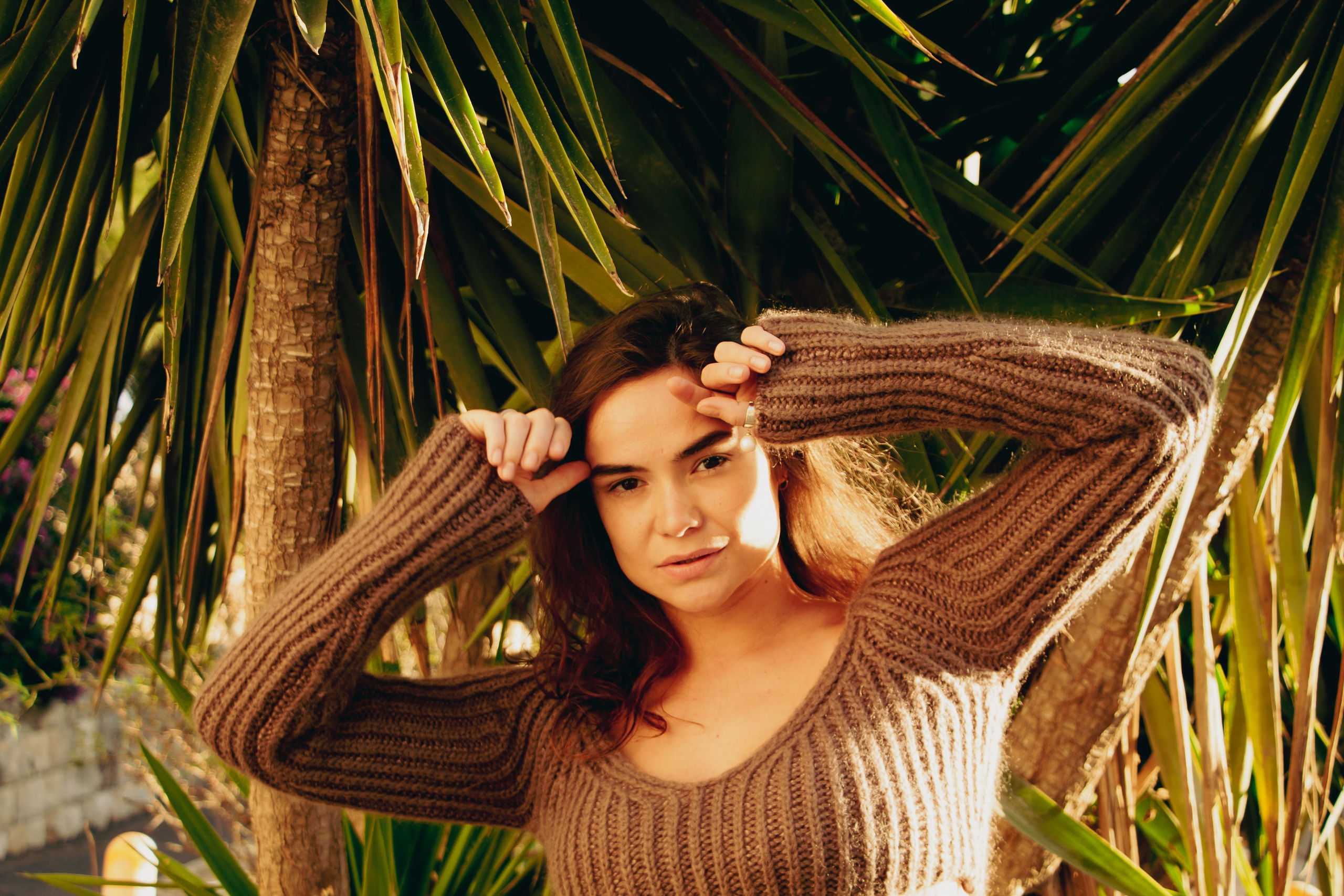 девушка подняла руки в верх, вокруг растут пальмы