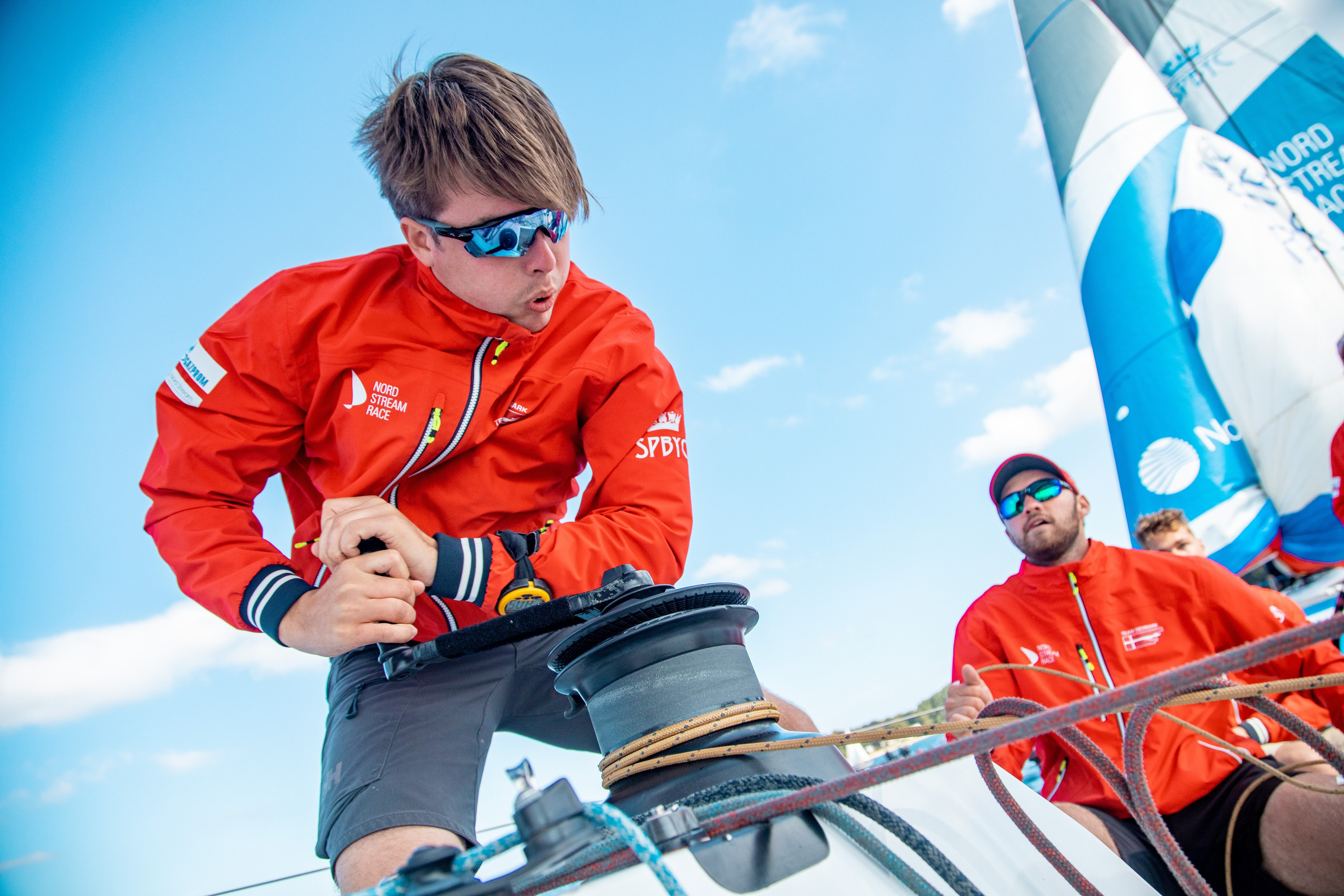 Триммер добирает шкот во время регаты. Фотограф на борту яхты.