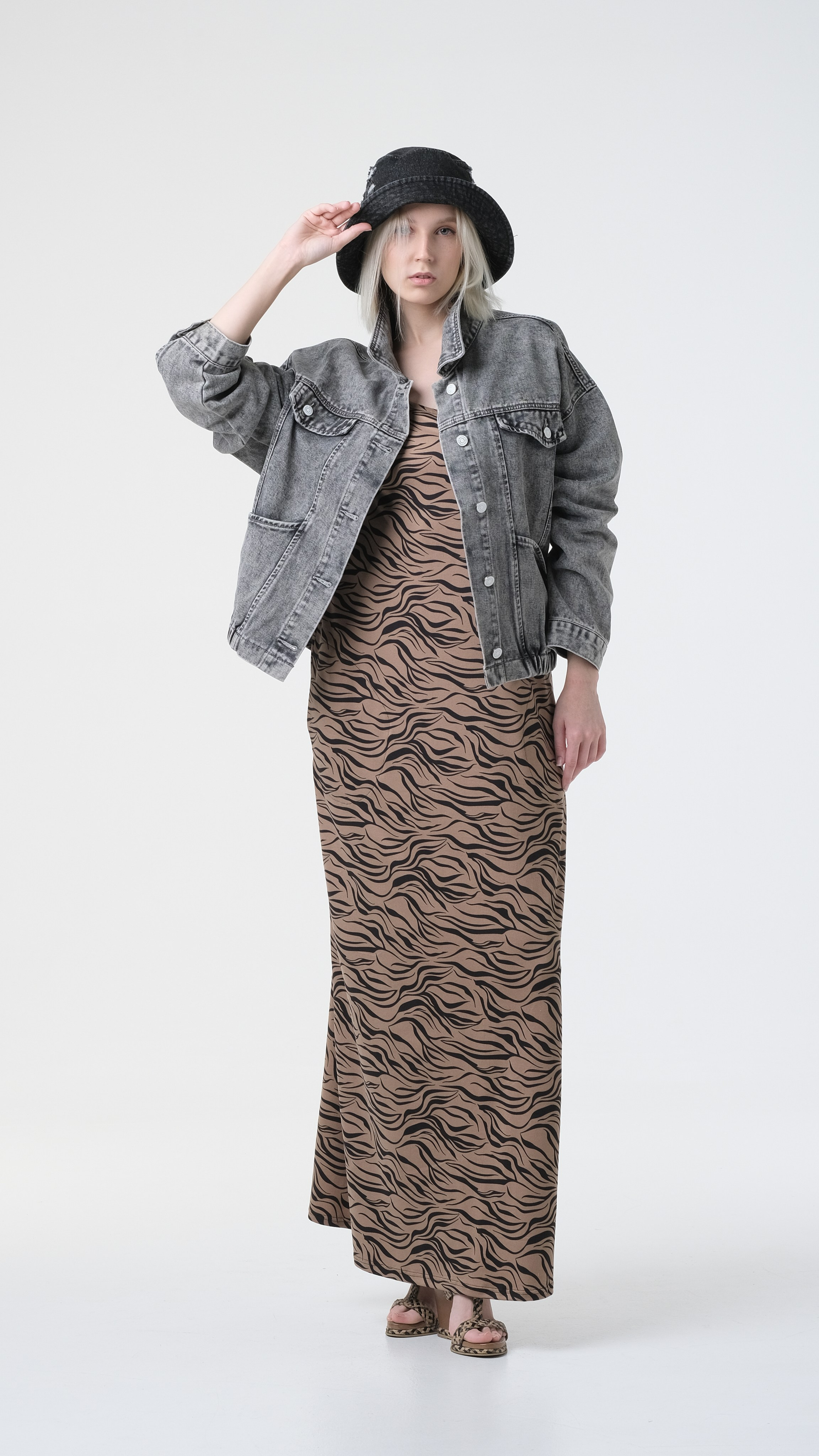 Фотография девушки во весь рост на циклораме. Сочетание длинного платья с джинсовой курткой и джинсовой панамой.