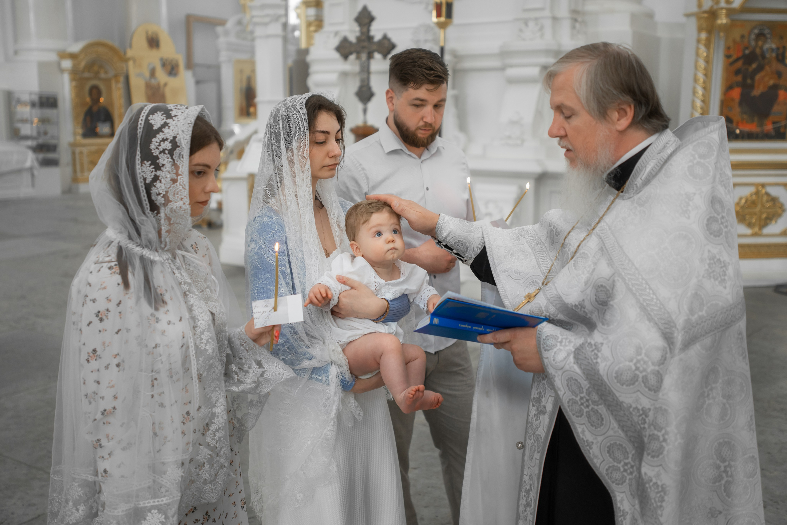 священник возлагает руку на малыша на таинстве крещения