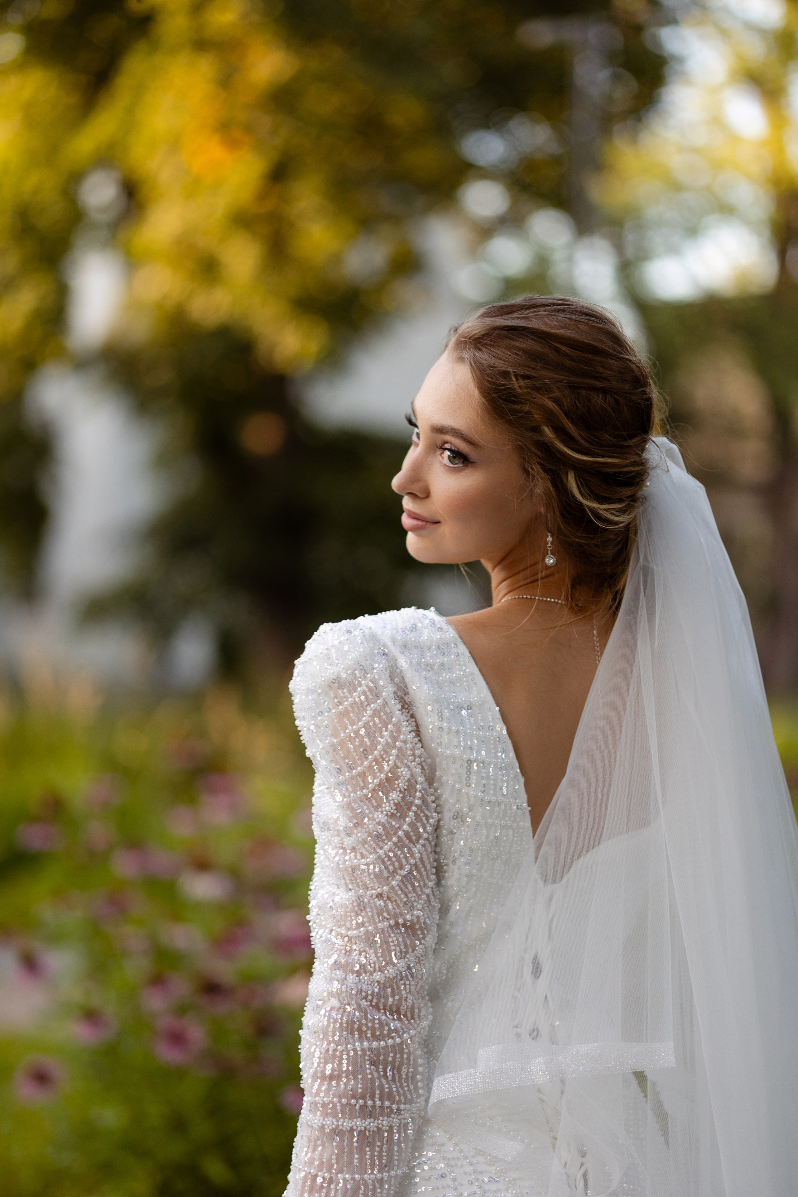 Невеста обернулась через плечо, сзади развивается вуаль.