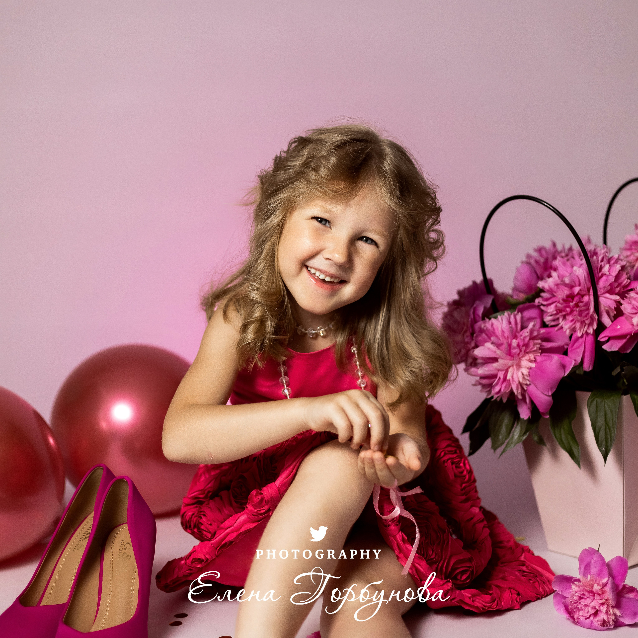 девочка модница в розовом с пионами раздувает блестки на фотосессии в студии