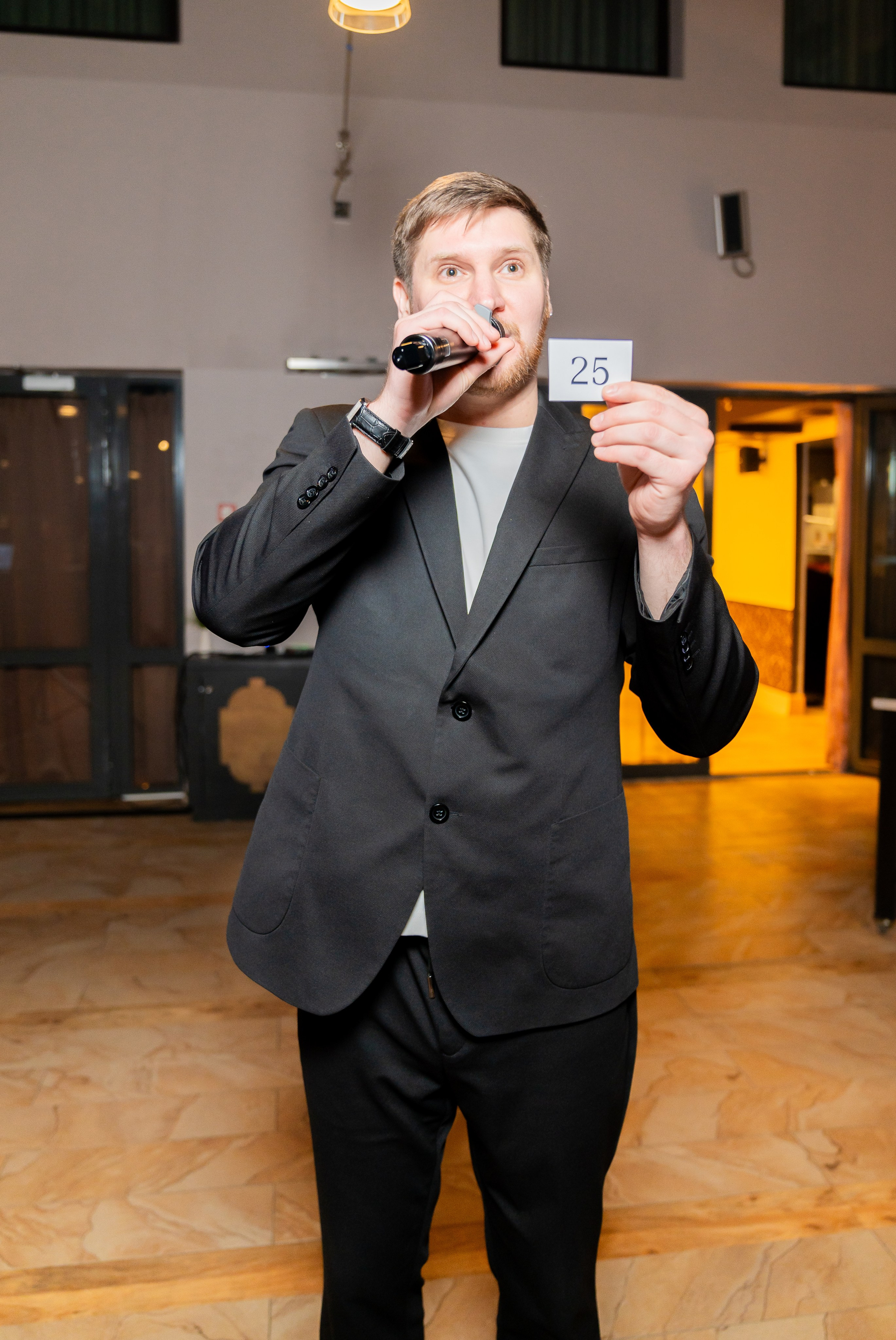 Ведущий объявляет победителя, поднимая карточку с номером 25 на розыгрыше в Radisson Sonya. Фото Евгения Мальцева (evrednix.ru).