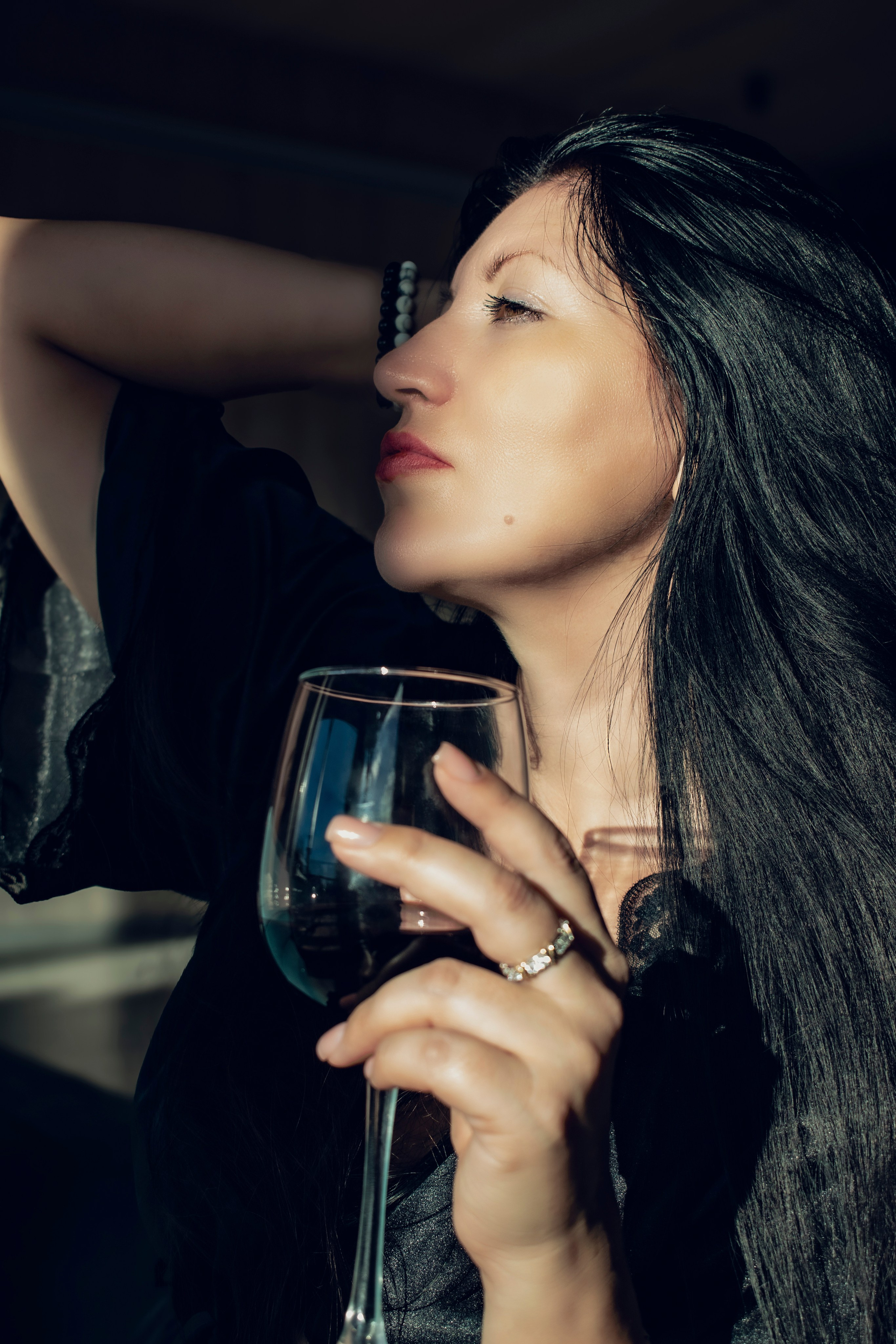 Девушка поправляет волосы, держа в руках бокал с вином