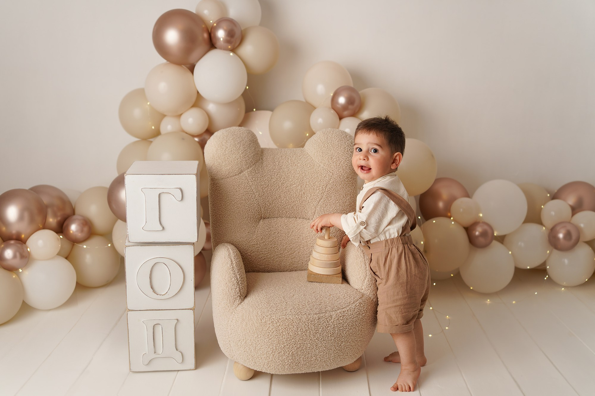 Детская фотосъемка - на фото малыш в нарядной одежде на фоне шариков.