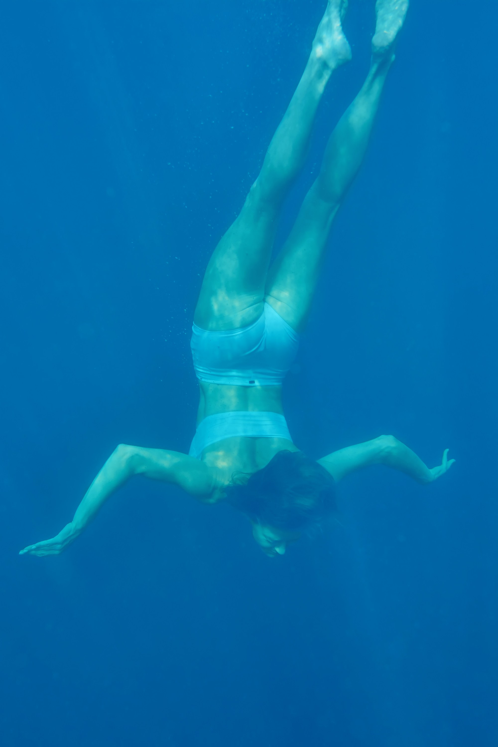 Девушка в купальнике ныряет и плывет под водой