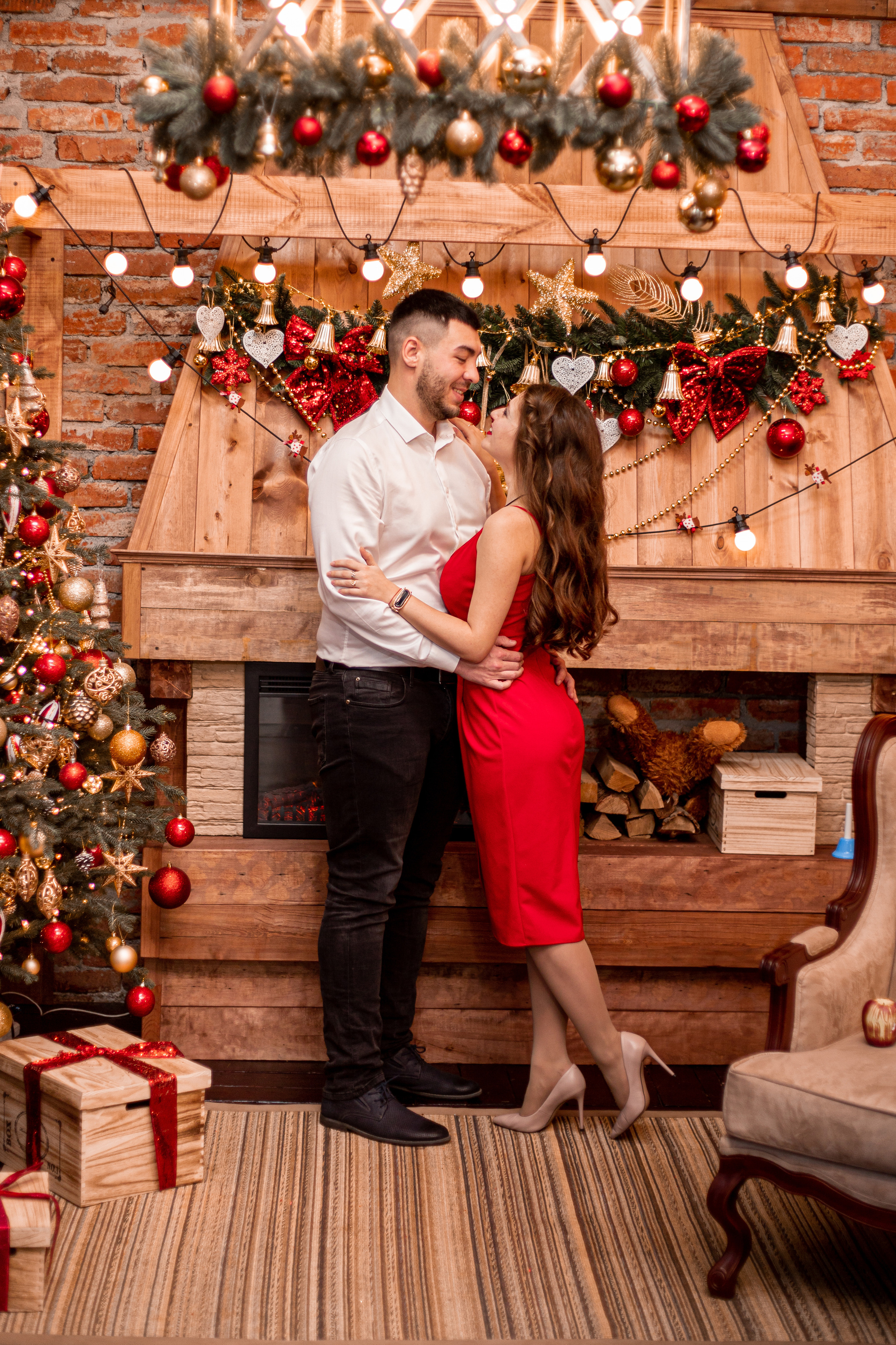 Красивая пара нежно смотрят друг на друга в студии DF обнимая друг друга на фоне камина в новый год Фотосессия в Уссурийске