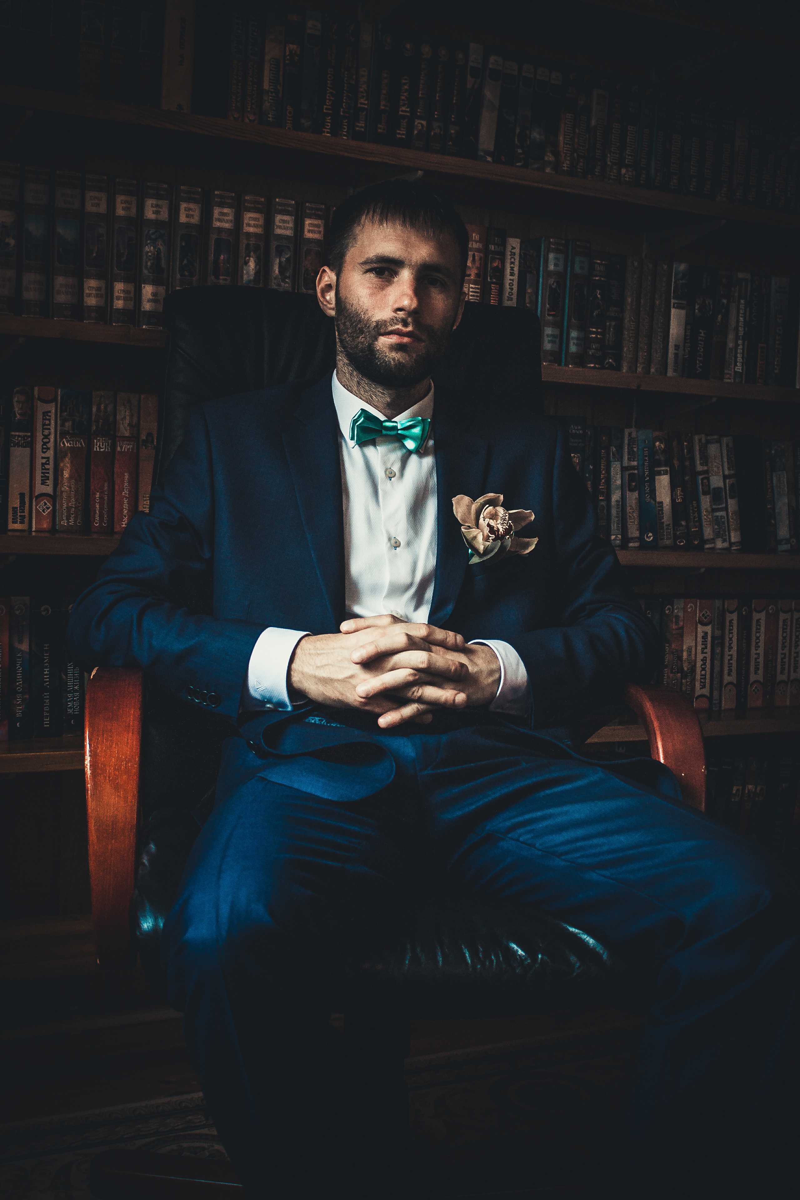 Жених сидит на кресле в кабинете на фоне книг Белый лебедь во Владивостоке свадебная фотосессия