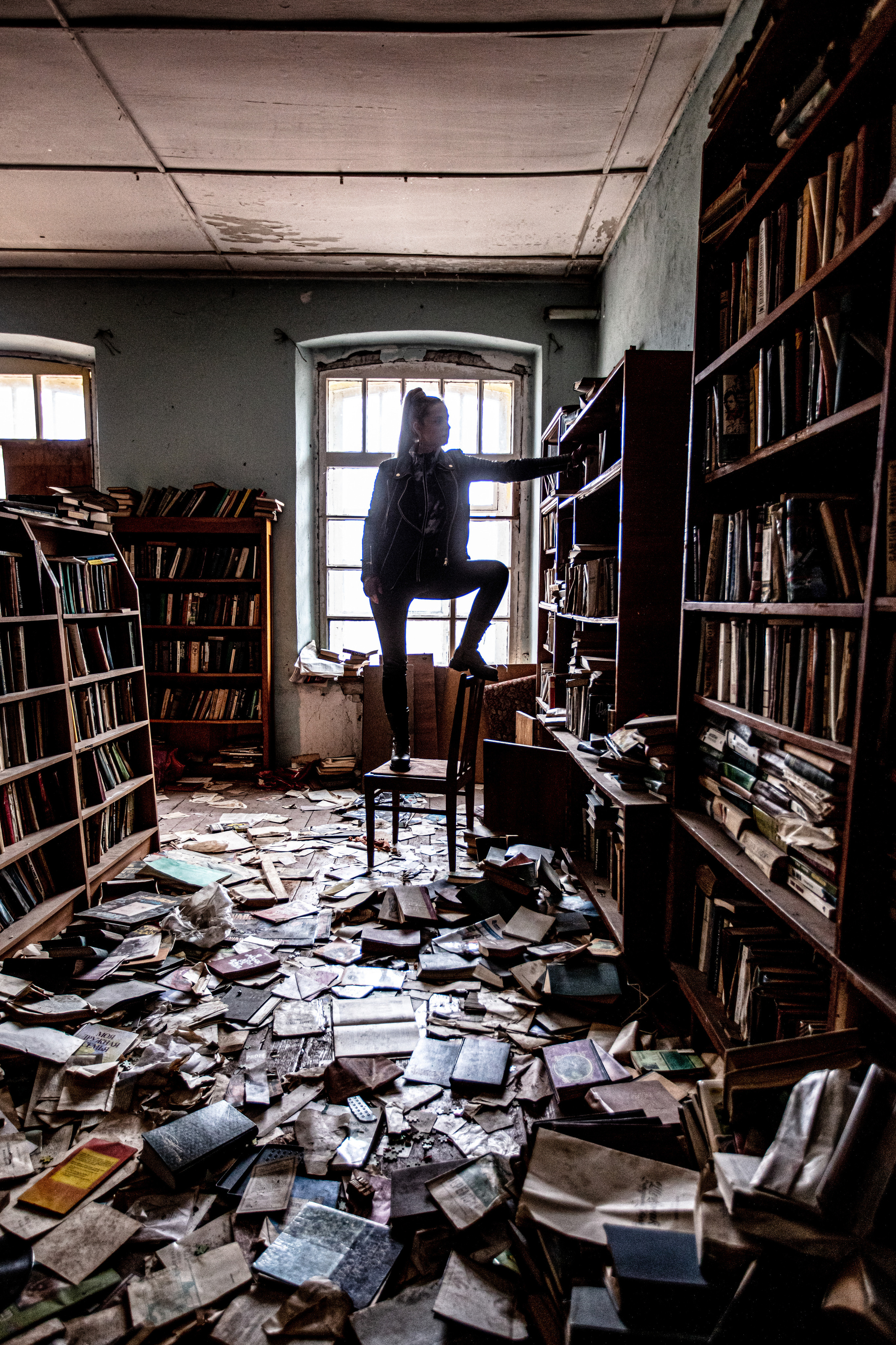 Девушка ищет на верхней полке книгу. Особенная фотосессия