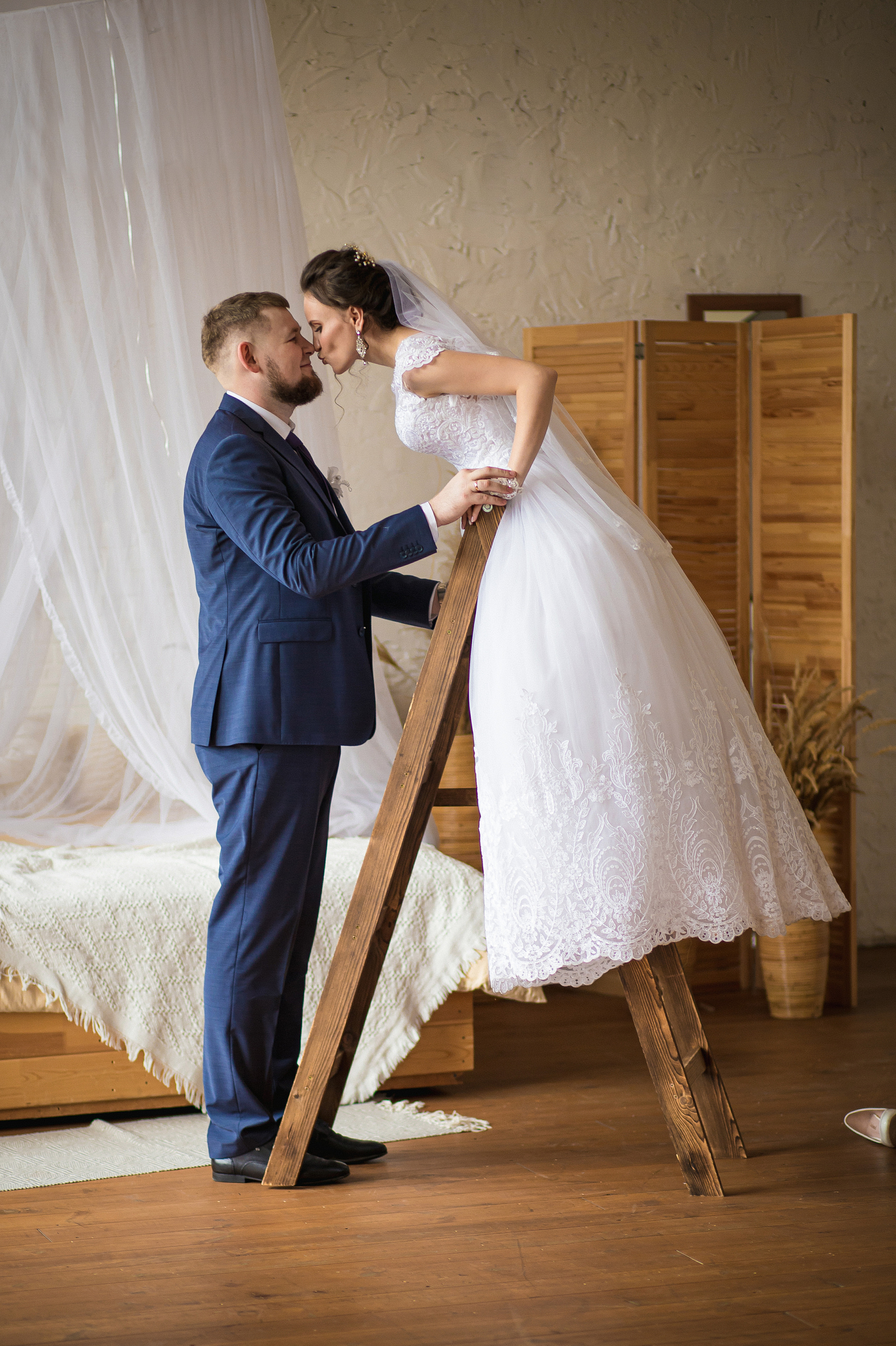 Невеста со стремянки целует жениха в студии в стиле сохо туфли во Владивостоке