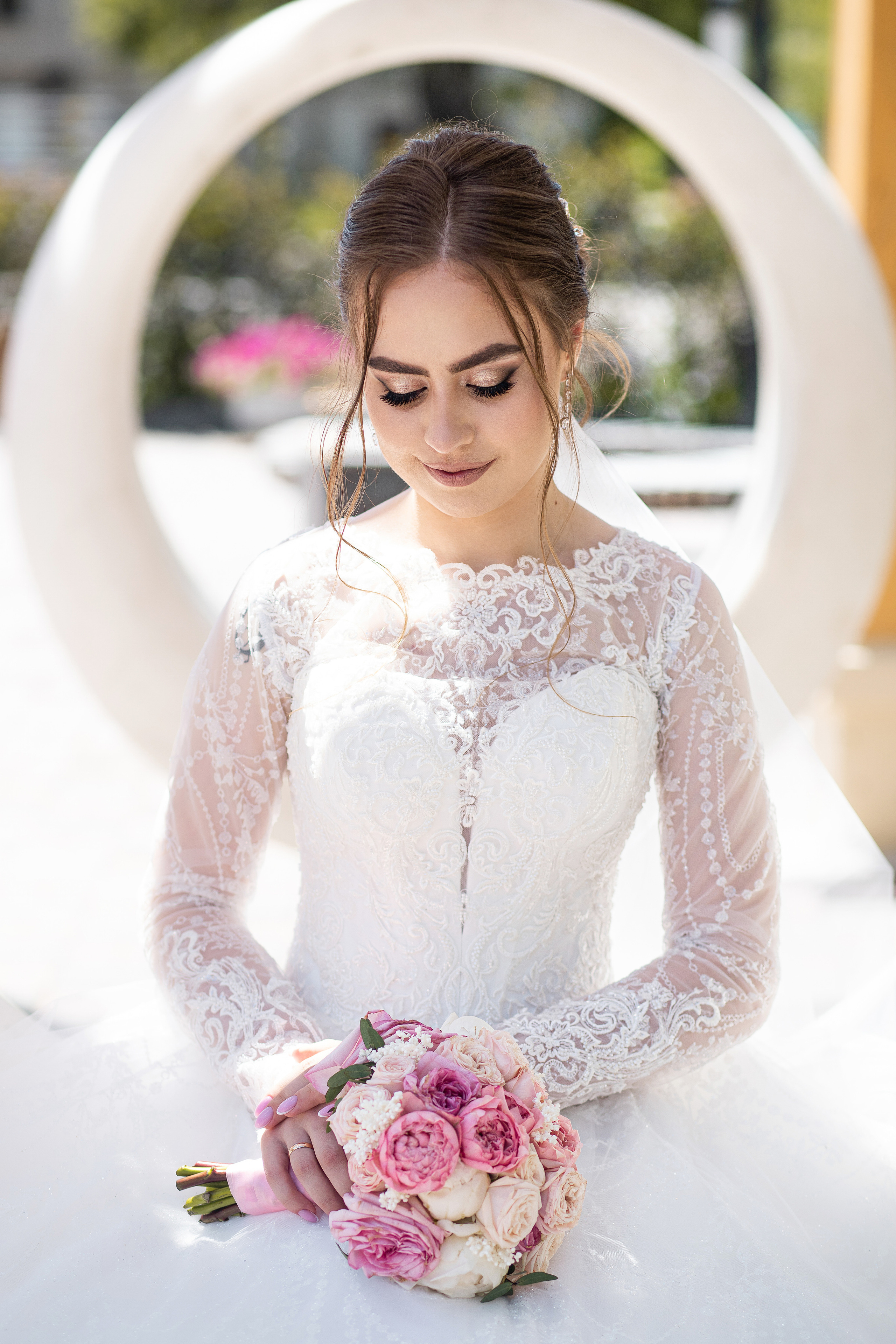 Нежная невеста робко опустила глаза на свой свадебный букет сидит на кольцевой качели в Пограничном