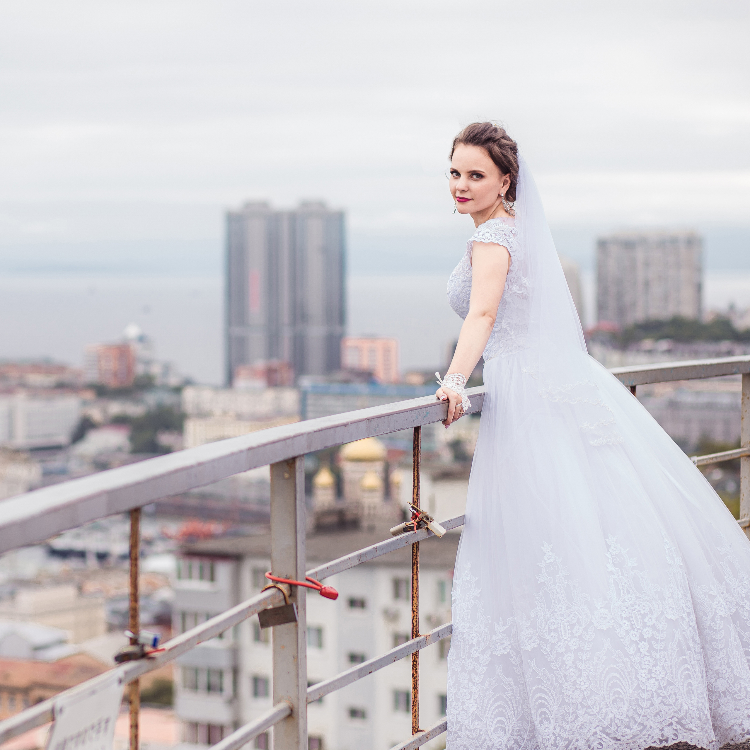 Невеста облокотилась на перилу смотровой фуникулёра во Владивостоке на фоне города