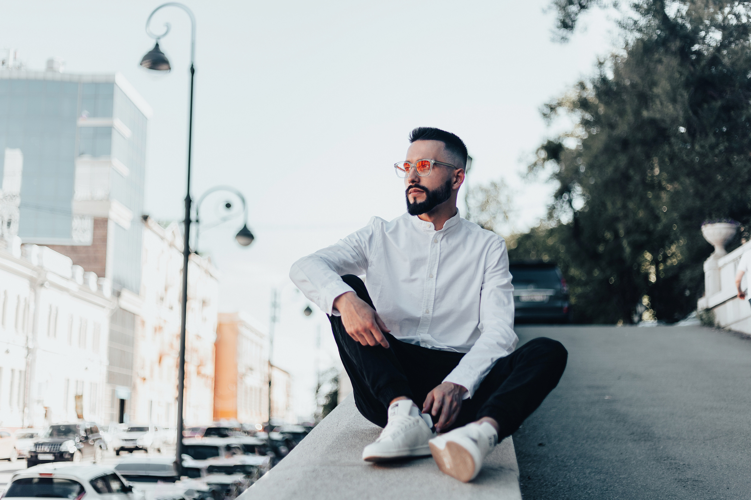 Мужчина в очках сидит на парапете дороги и смотрит в даль около гостиницы серая лошадь во владивостоке